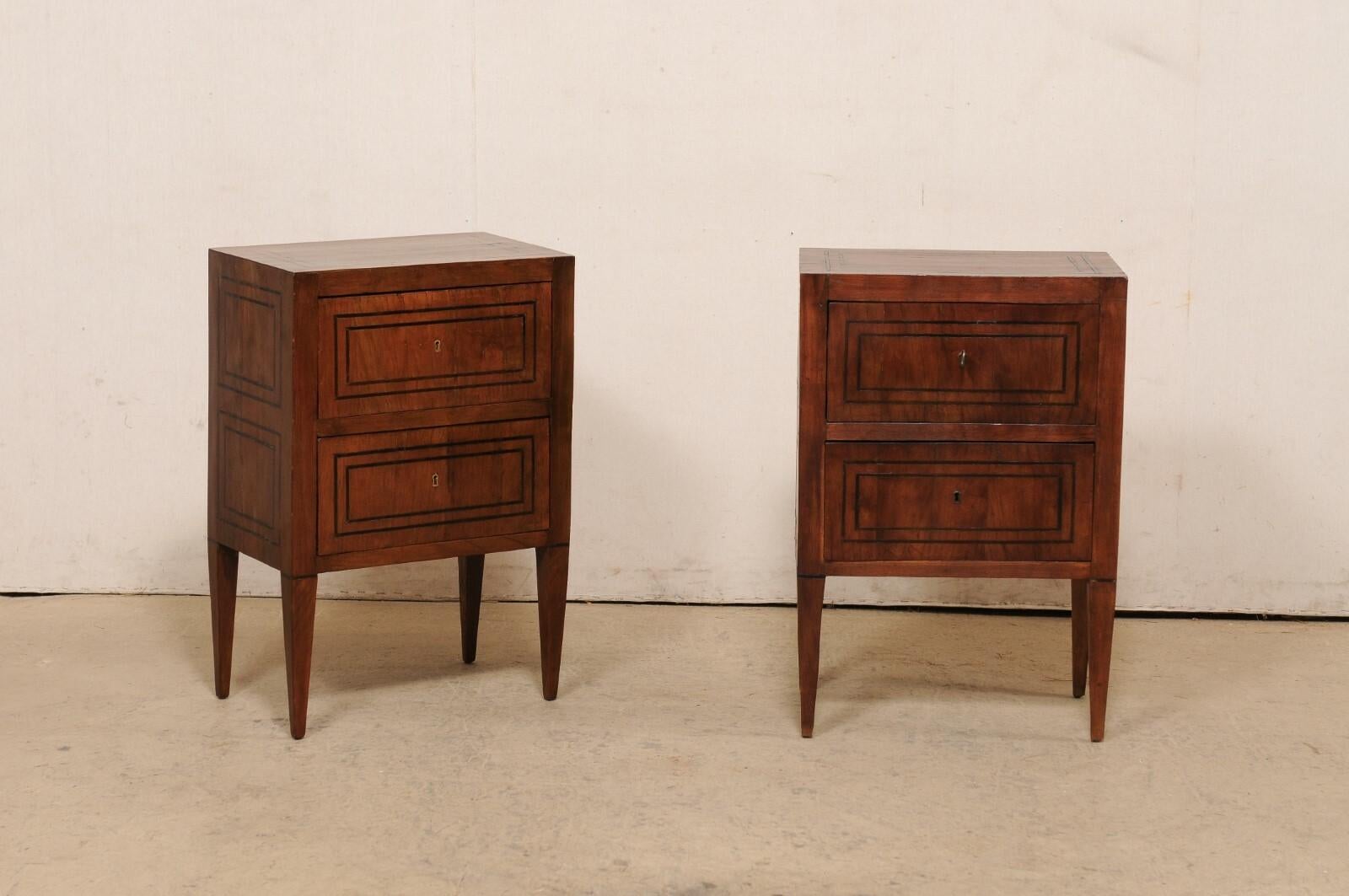 An Italian pair of two-drawer raised side chests with inlay banding, from the early 19th century. These antique smaller-sized chests from Italy have been designed in nice, clean/linear lines, allowing the beautifully veneered wood grain and inlay