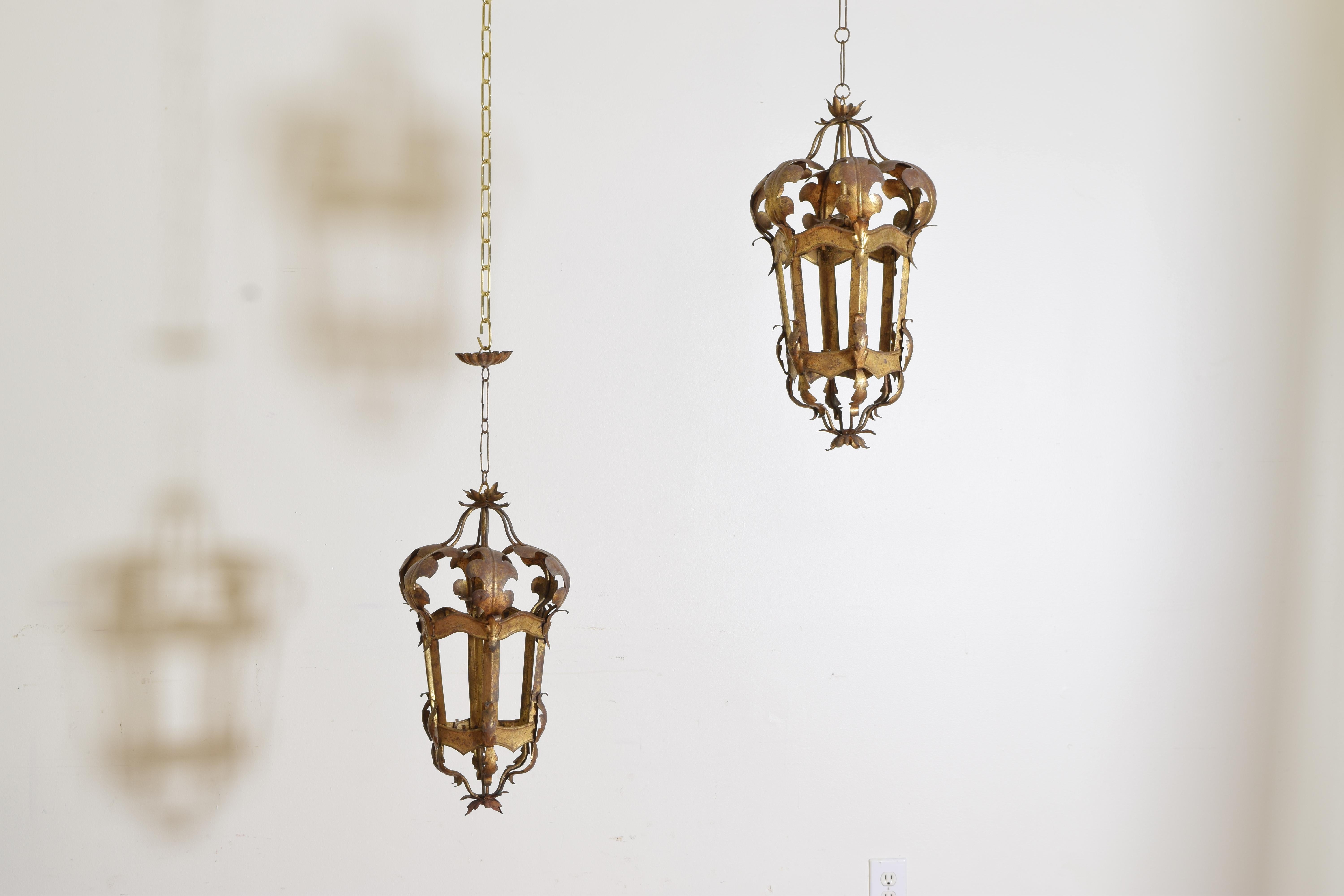 A decorative pair of Venetian-style gilt metal lanterns. The pair with bottoms ending in leaves. Having six windows with notches for glass if desired are shaped and connected to the top by bulbous shaped leaves.
