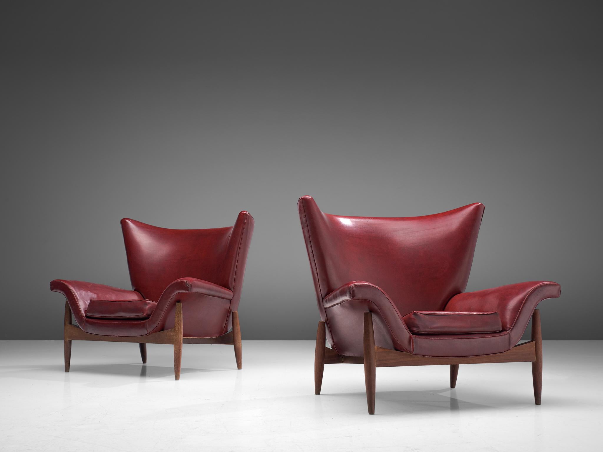 Pair of wingback chairs, leatherette and wood, Italy, 1960s

A stunning pair of Italian lounge chairs, characterized by their large, curved backs and the pointy edges. The corners of the backrests point upwards, giving these chairs a theatrical