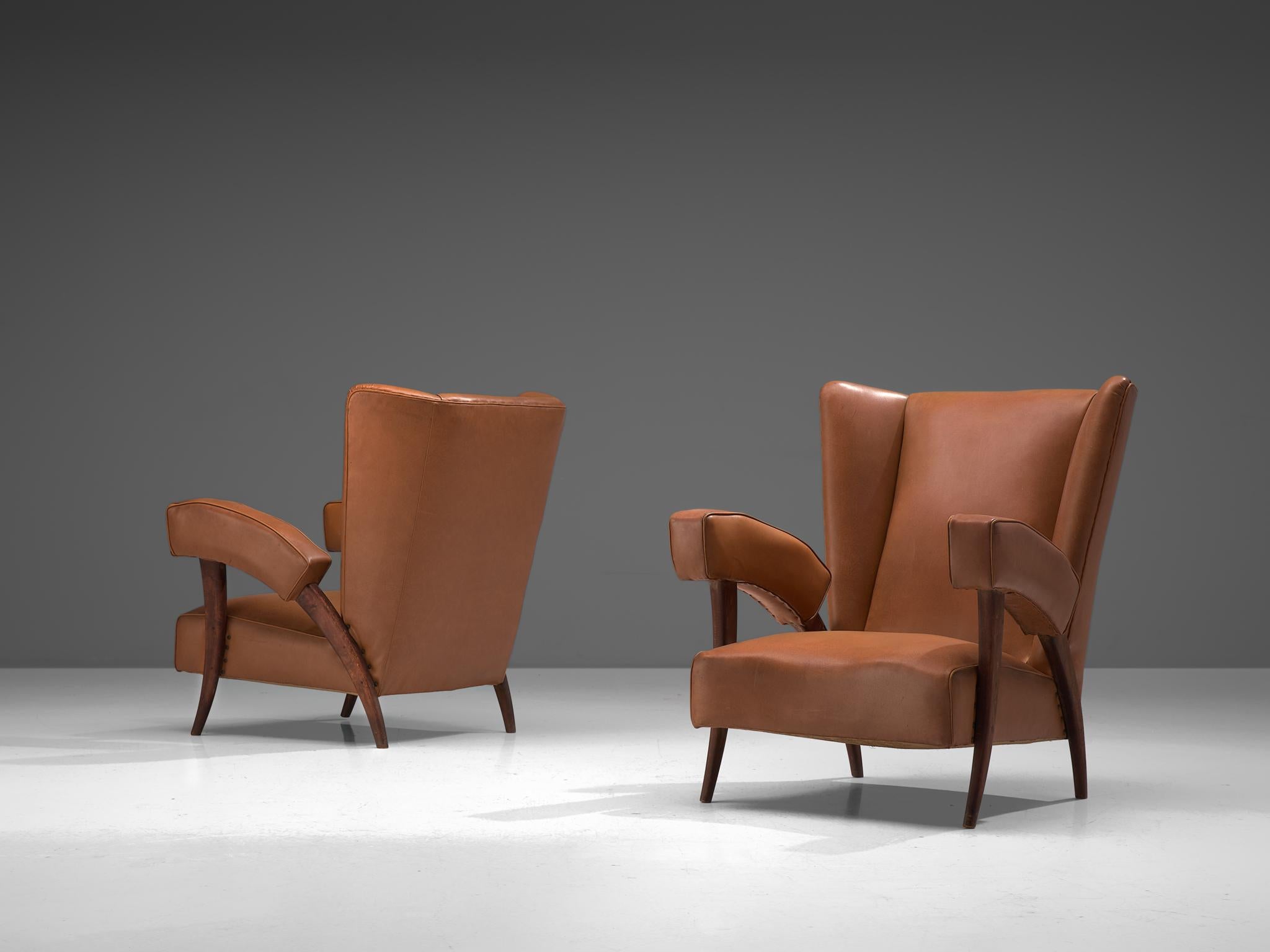 Set of 2 high back chairs to be reupholstered, fabric and darkened oak, Italy, 1950s.

Stunning set of Italian lounge chairs featuring high wingbacks. The chairs are comfortable in their design, featuring a wide seat and a tilted backrest. The
