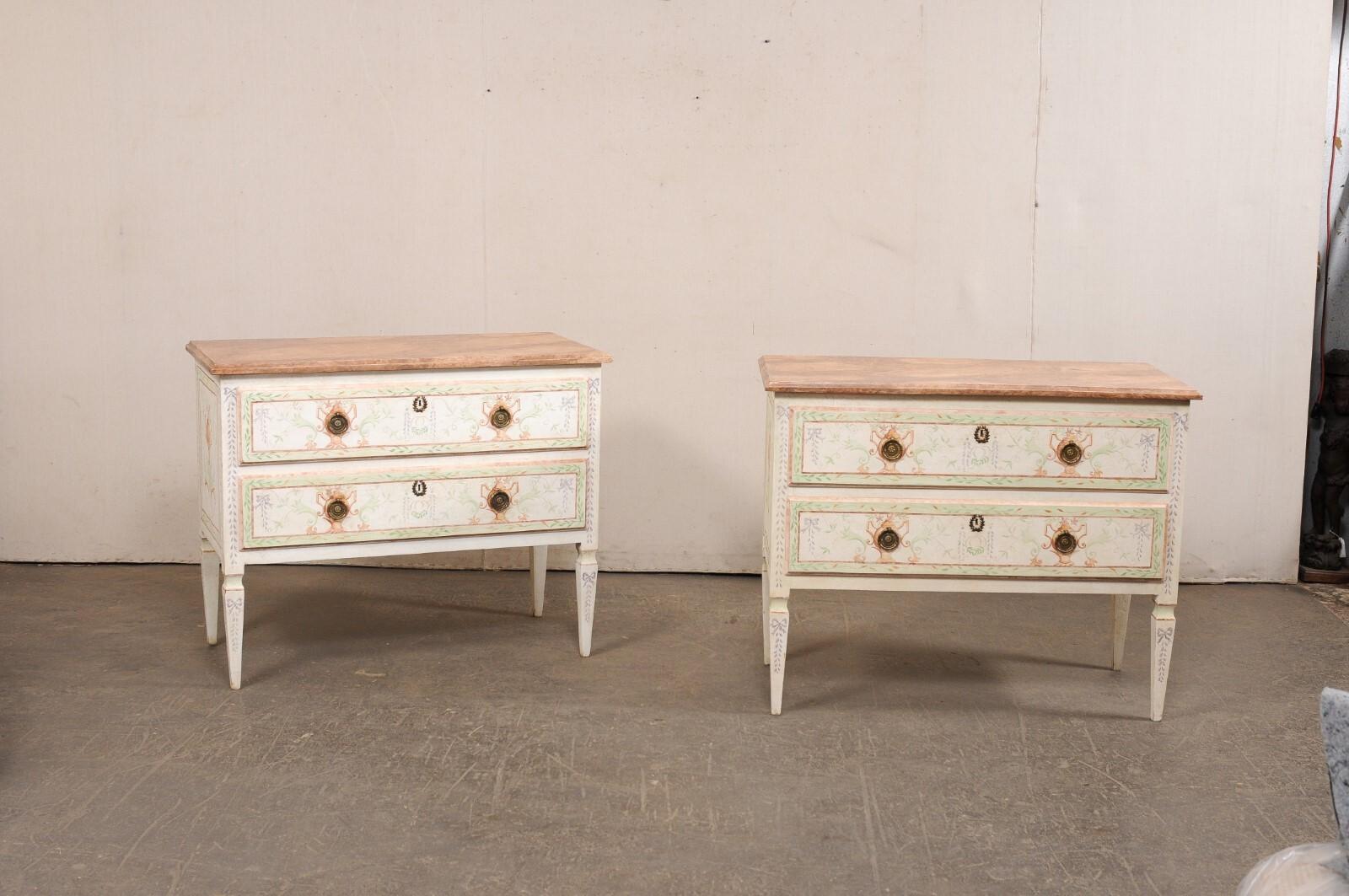 An Italian pair of Neoclassical inspired, hand-painted console chests, with faux-marble tops. This pair of vintage cassettiere (Italian for chests of drawers) from Italy each features a rectangular-shaped faux-marble painted top, over a case which