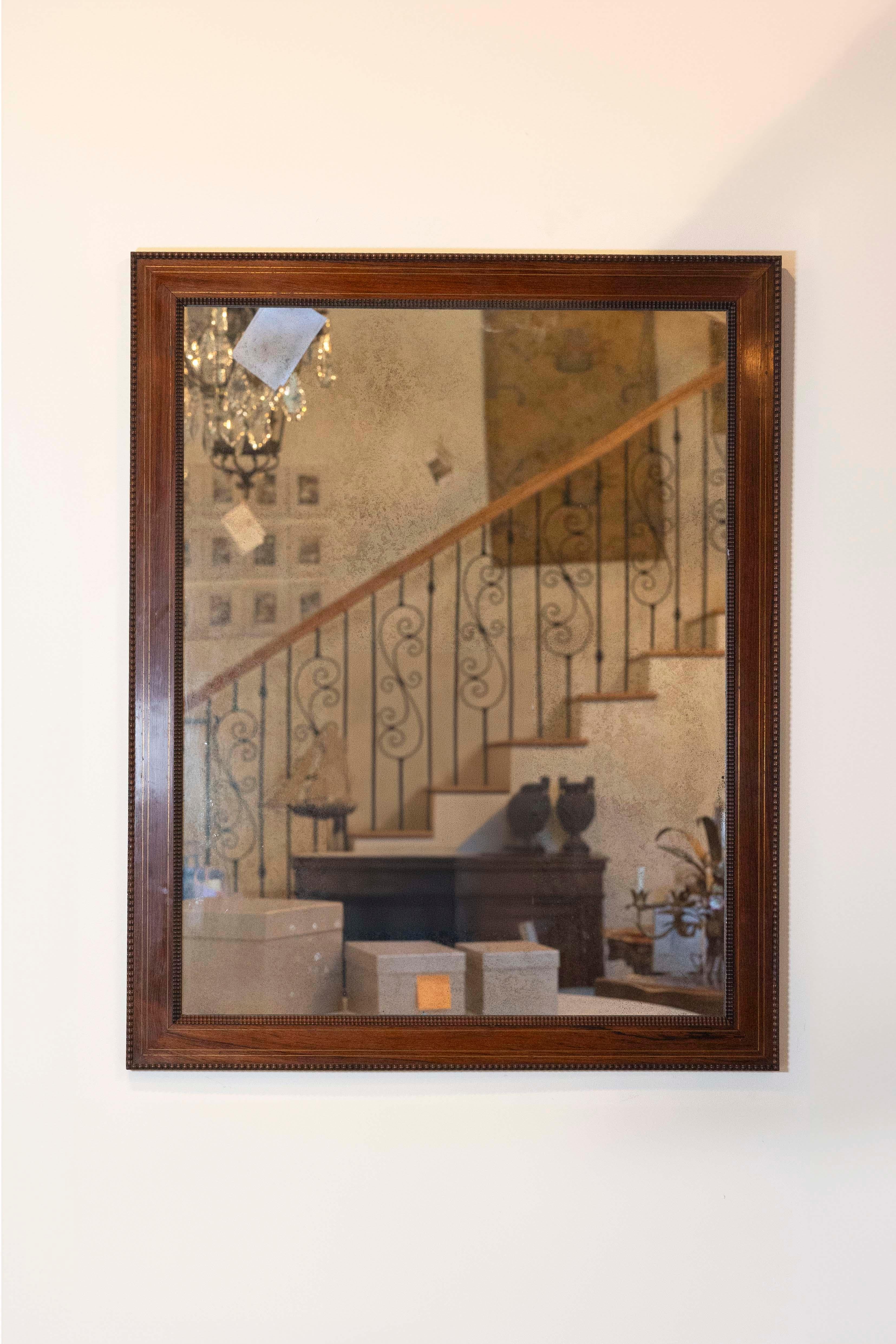 This Italian palisander mirror from the 20th century is a stunning piece featuring a carved frame, subtle gilt accents, and a contemporary mirror plate. Made in Italy, this mirror showcases a sleek, linear silhouette that highlights the luxurious