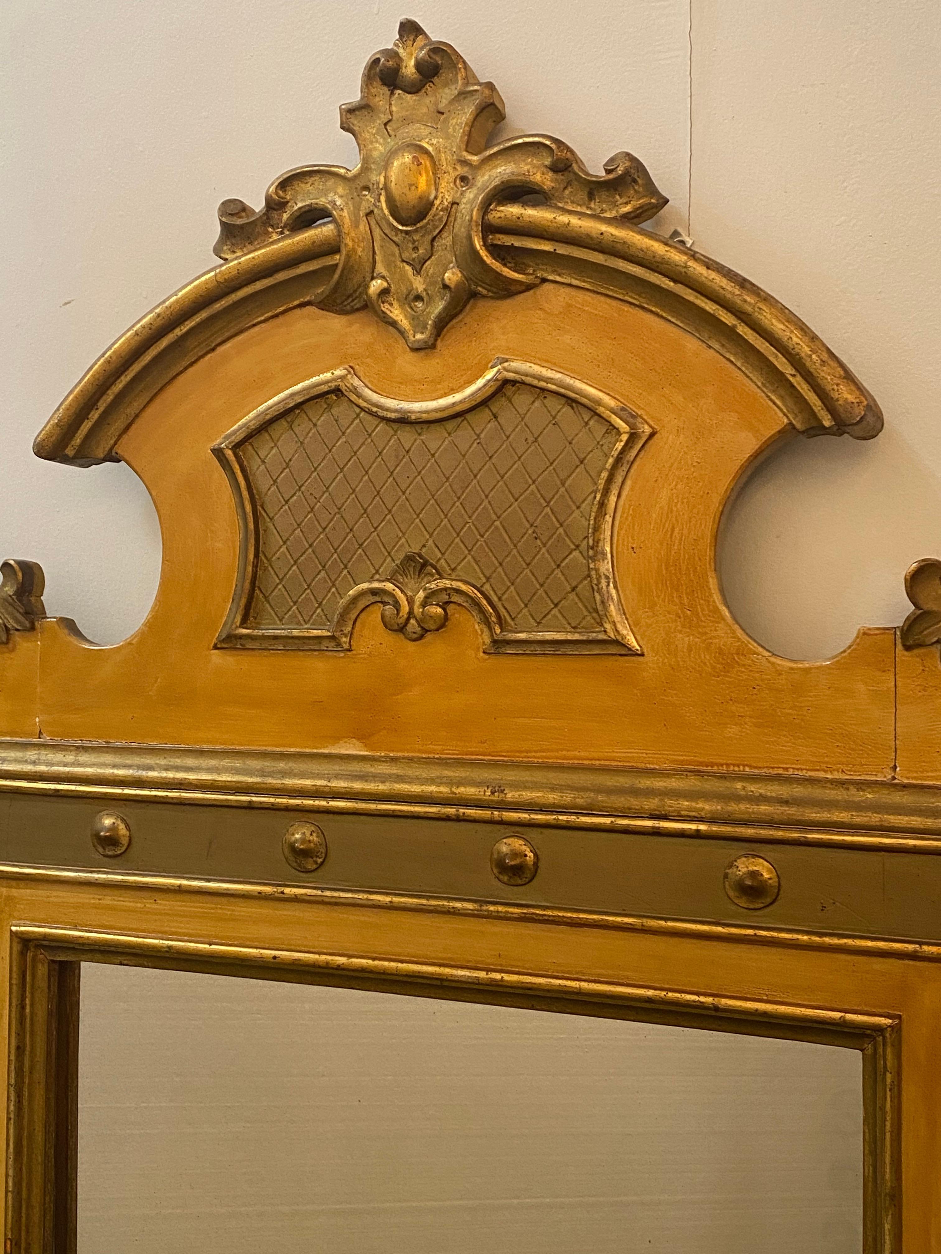 Italian parcel gilt wall mirror, 20th c., central cartouche crest, scrolled foliate corners, centering flat mirror plate.