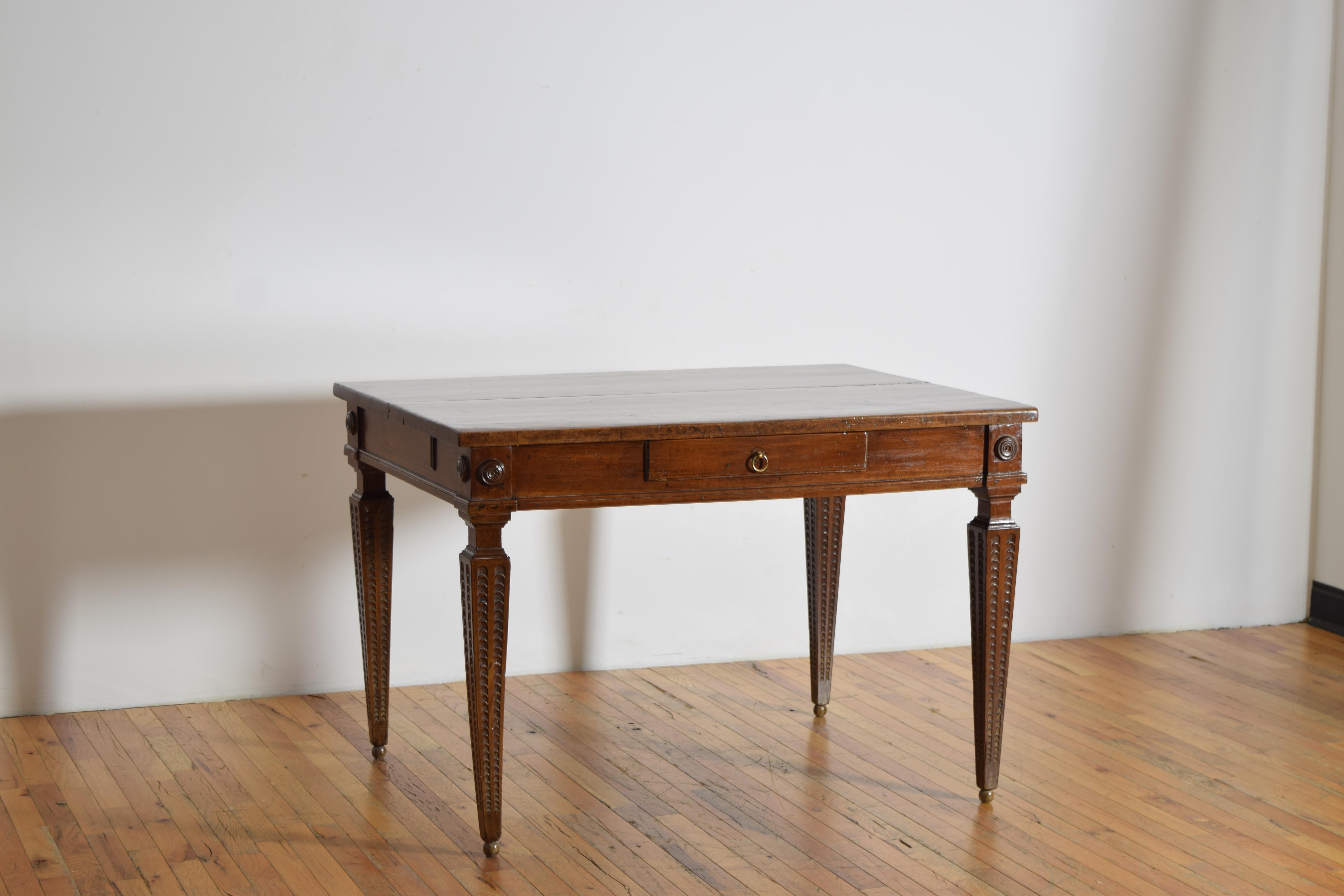 constructed entirely of solid walnut, the thick two piece top resting on a conforming case housing one drawer and three faux drawers, all of the corners with turned roundels, the the large square tapering legs being the special feature with