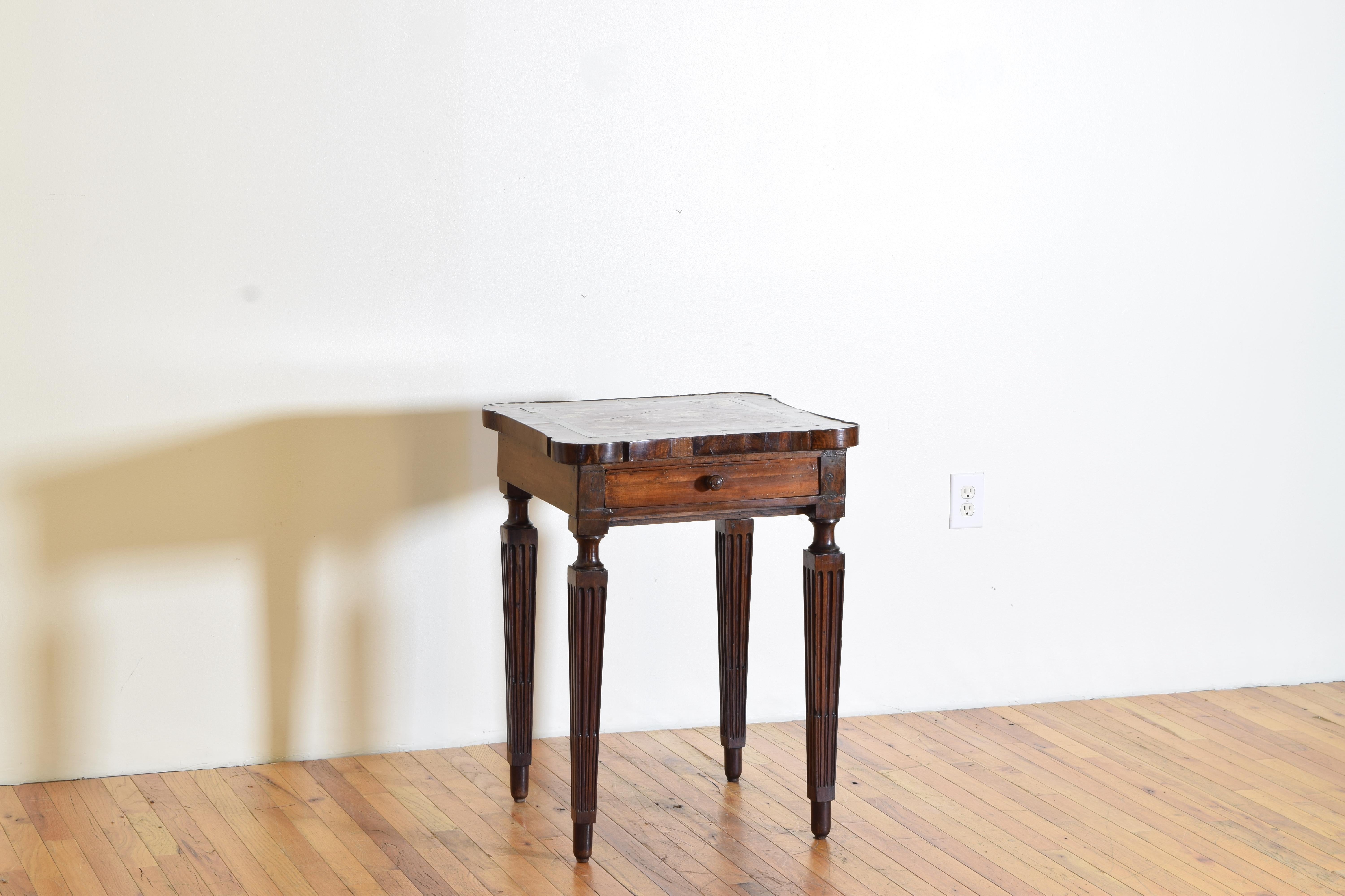 A very rare table with a uniquely shaped top with concave sides and rounded corners, thick veneers, the inset marble top of a rare shade, the case housing a lone drawer and raised on fluted carved square tapering legs ending on shaped feet.