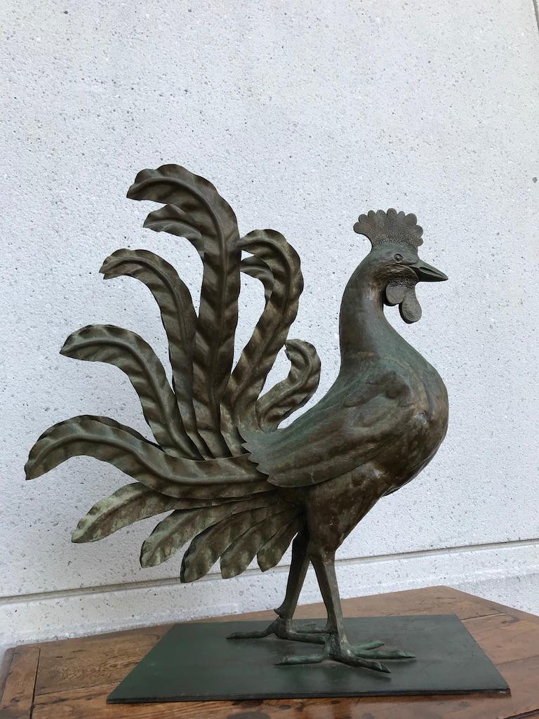 Very cool hand wrought iron and tin rooster, the bird shown strutting and showing off his regalia of life-like feathers. Large scale at 28 by 26 by 12 inches. 
You can see this rooster as a prop in the 1965 Steve McQueen movie, 