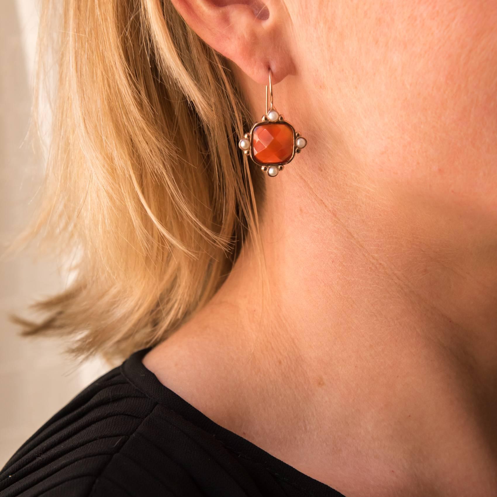 For pierced ears.
Earrings in vermeil, silver and rose gold.
Sleeper earrings, each is set with a faceted orange crystal surrounded by 4 white glass pearls closed set on both sides. The clasp is a gooseneck with safety hook.
Height: 3.2 cm, width: 2