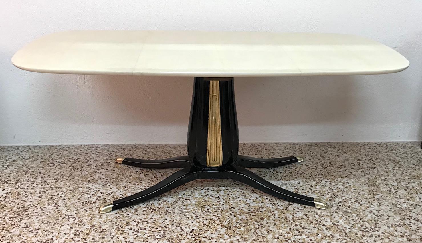 This table was produced in the 1950s in Italy in the manner of Osvaldo Borsani.
The top is completely covered with fine parchment while the base is black lacquered with the central part in gold leaf.
The tips of the legs are made of brass.