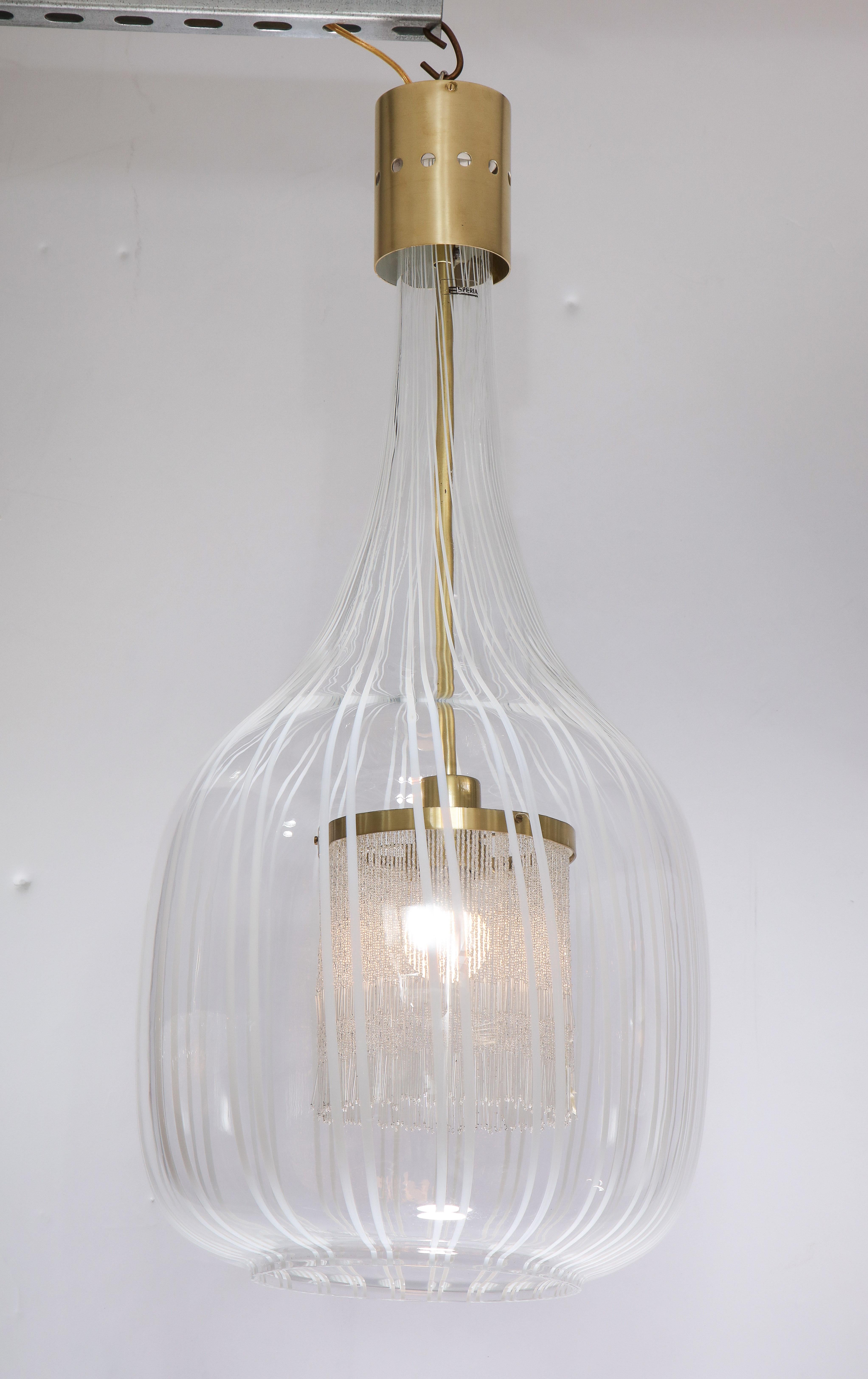 Un lustre suspendu unique et magnifique du designer Angelo Brotto (1914-2002), réalisé pour Esperia en verre soufflé de Murano avec des lignes verticales blanches. L'intérieur est équipé d'une frange qui entoure l'ampoule, créant une lueur