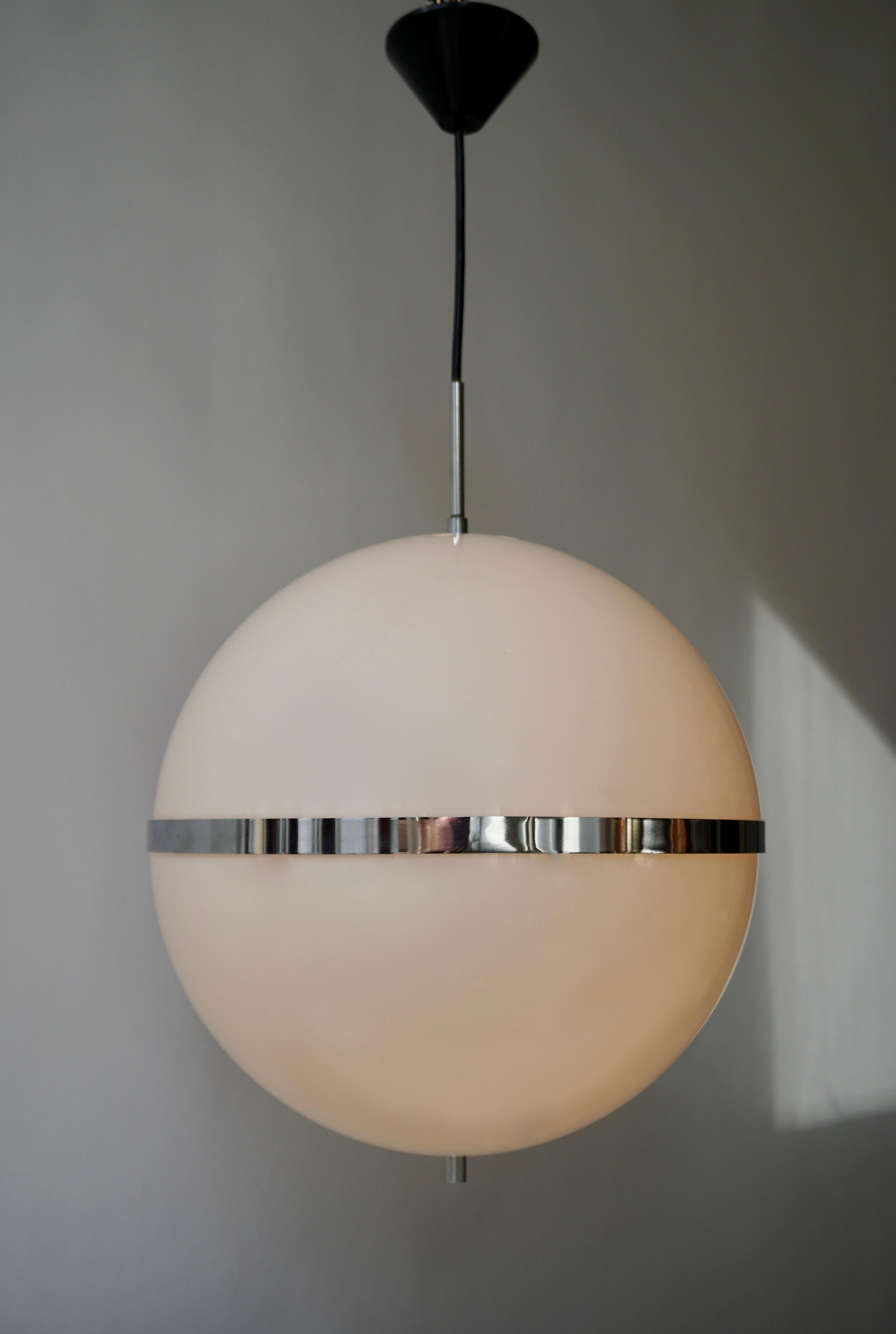 Rare and large pendant lamp in the style of Harvey Guzzini, Italy, 1960s-1970s. The light consists of a large sphere shaped shade in milky white plastic. These two parts are being complemented with beautiful chrome-plated metal details. This amazing