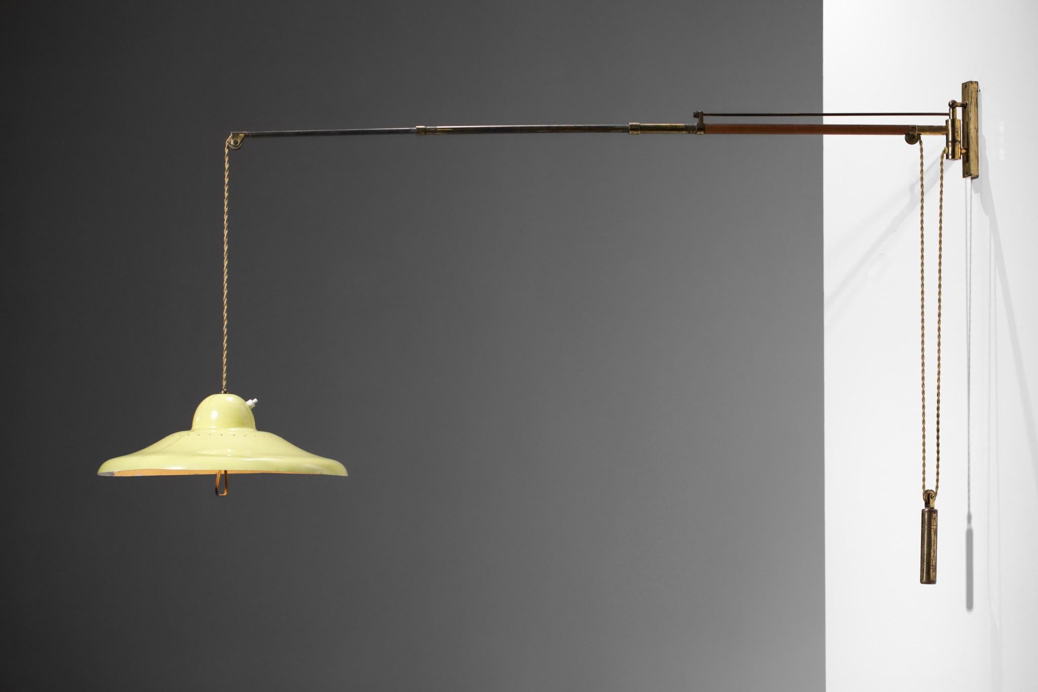 Italian telescopic wall light from the 1950s in the style of Arredoluce's work. Structure and counterweight in brass, shade in yellow lacquered steel. Counterweight and pulley to modulate the height of the lampshade and the length of the bracket