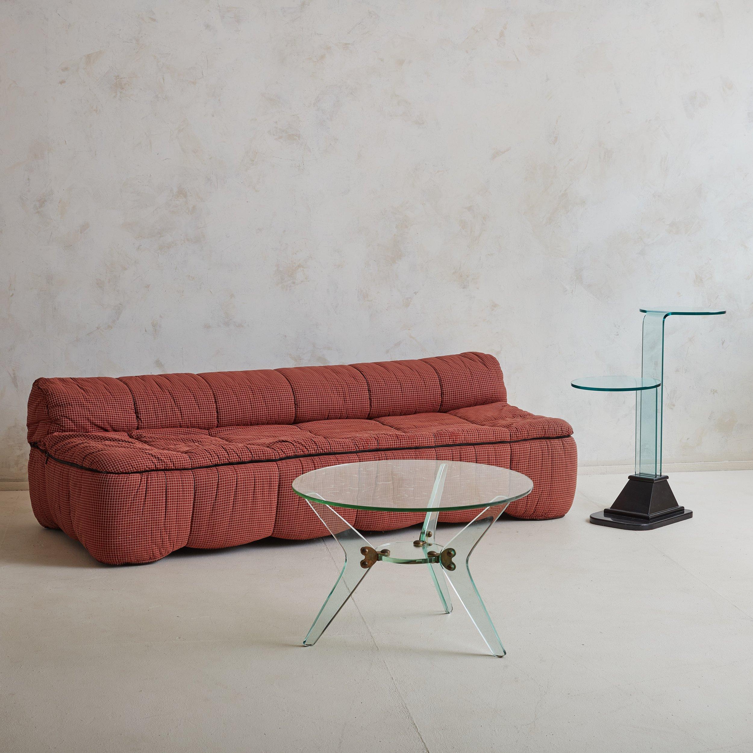 A petite Italian round glass cocktail table in the style of Fontana Arte. This cocktail table features a tripod base with sculptural boomerang legs and a round glass top. Natural patinaed bronze hardware secures the piece, adding beautiful contrast