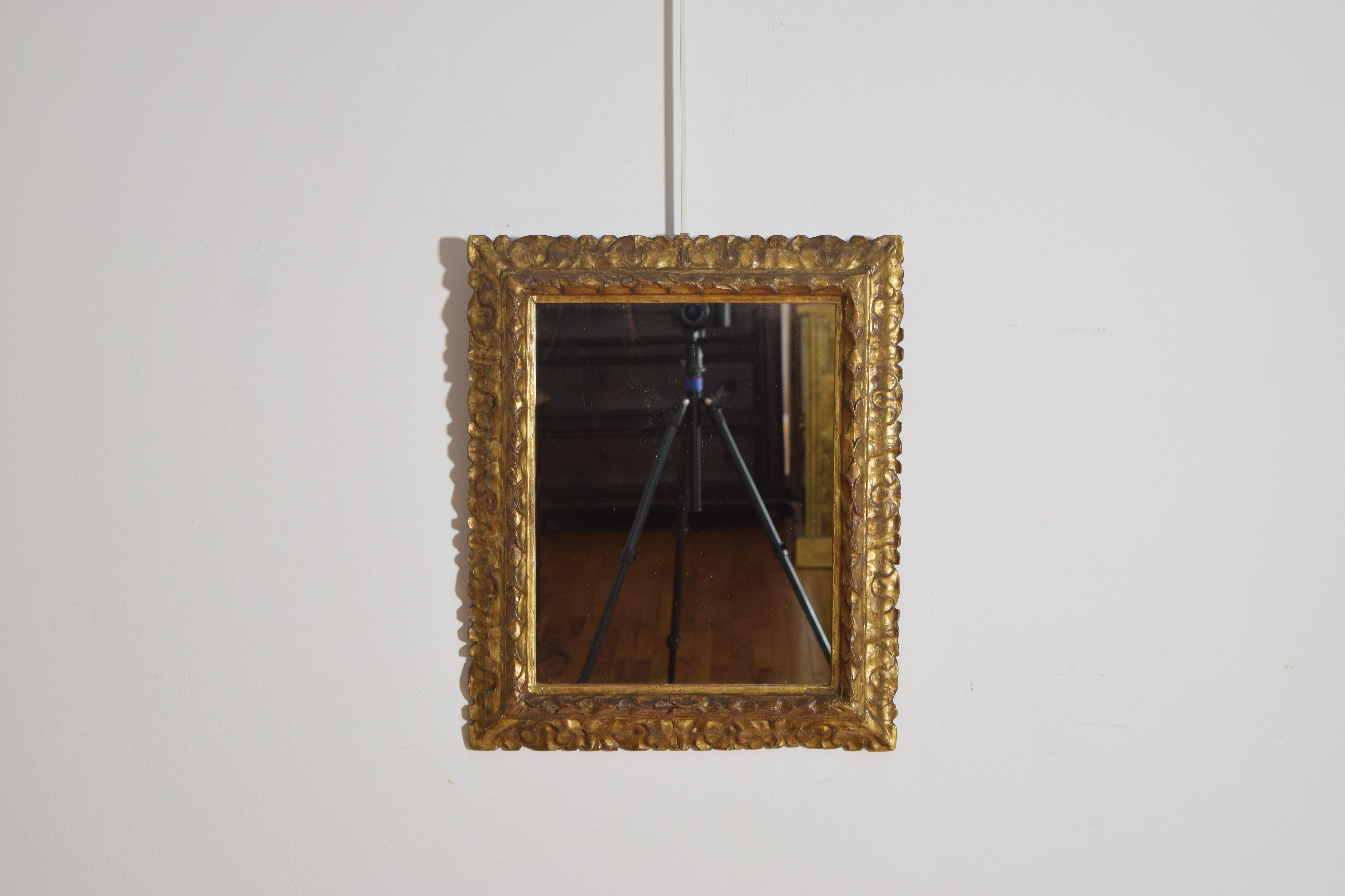 marco rectangular con tallas en forma de hoja y de laurel, superficies recubiertas de pan de oro, ahora con una placa de espejo moderna
