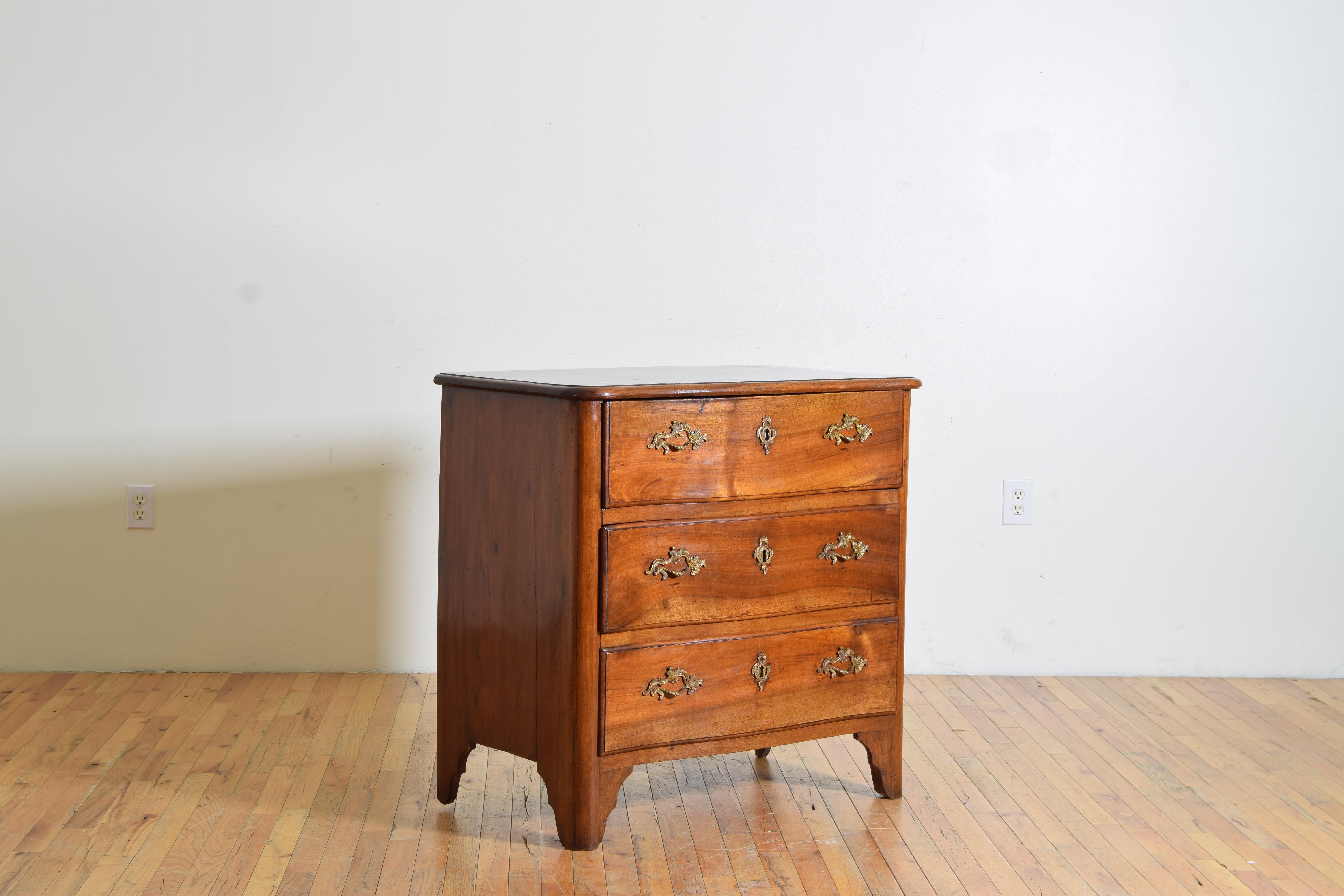 Con un piano a forma di serpentina con bordo modellato sopra una cassa rettangolare che ospita tre cassetti con ferramenta decorativa in ottone, sollevata su piedi a staffa sagomati.