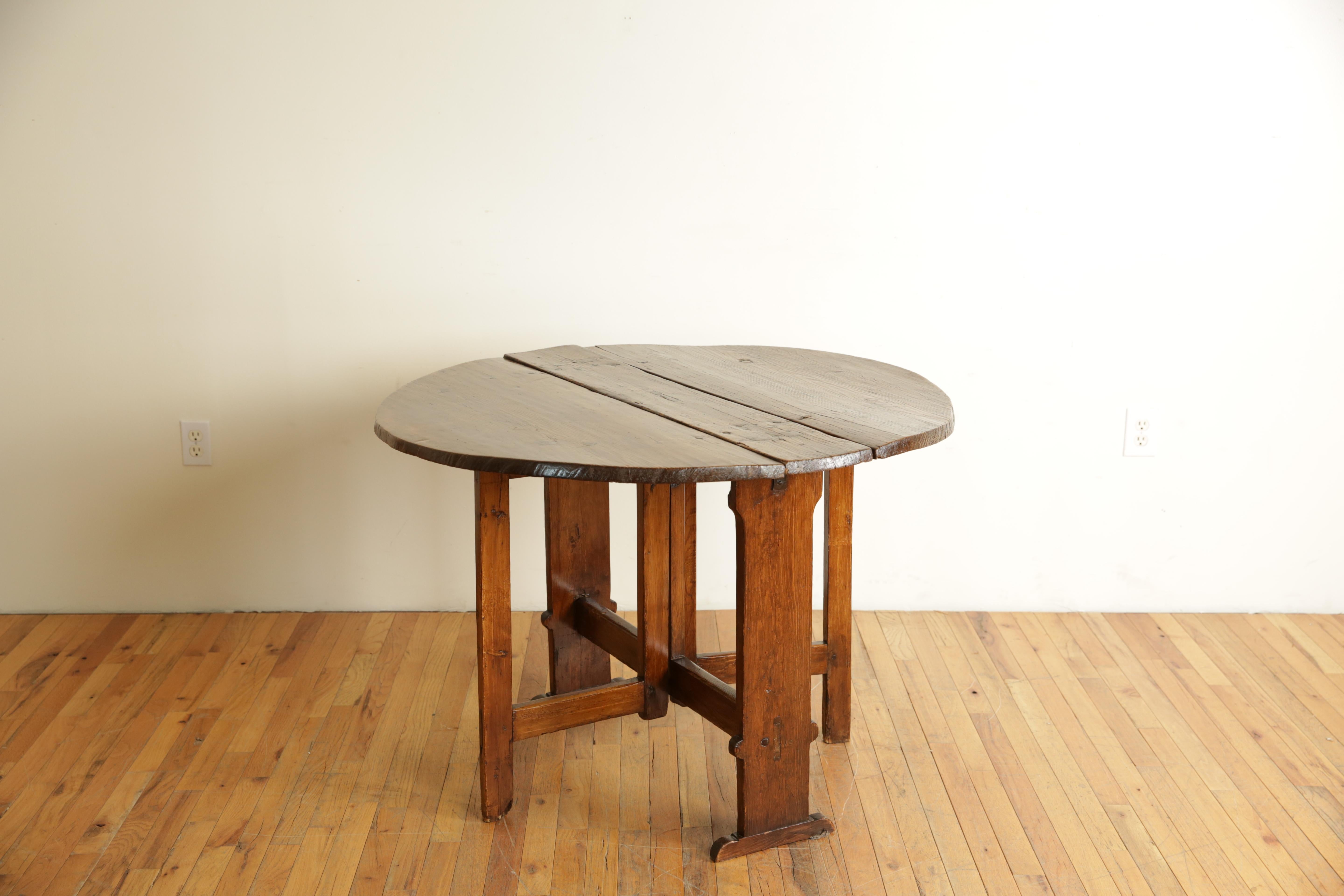 Constructed entirely of chestnut (Castagno) and featuring a three piece top the sides folding down as the third and fourth legs swing into support positions, raised on trestle form legs joined by a straight stretcher, Center section measures h. 30,