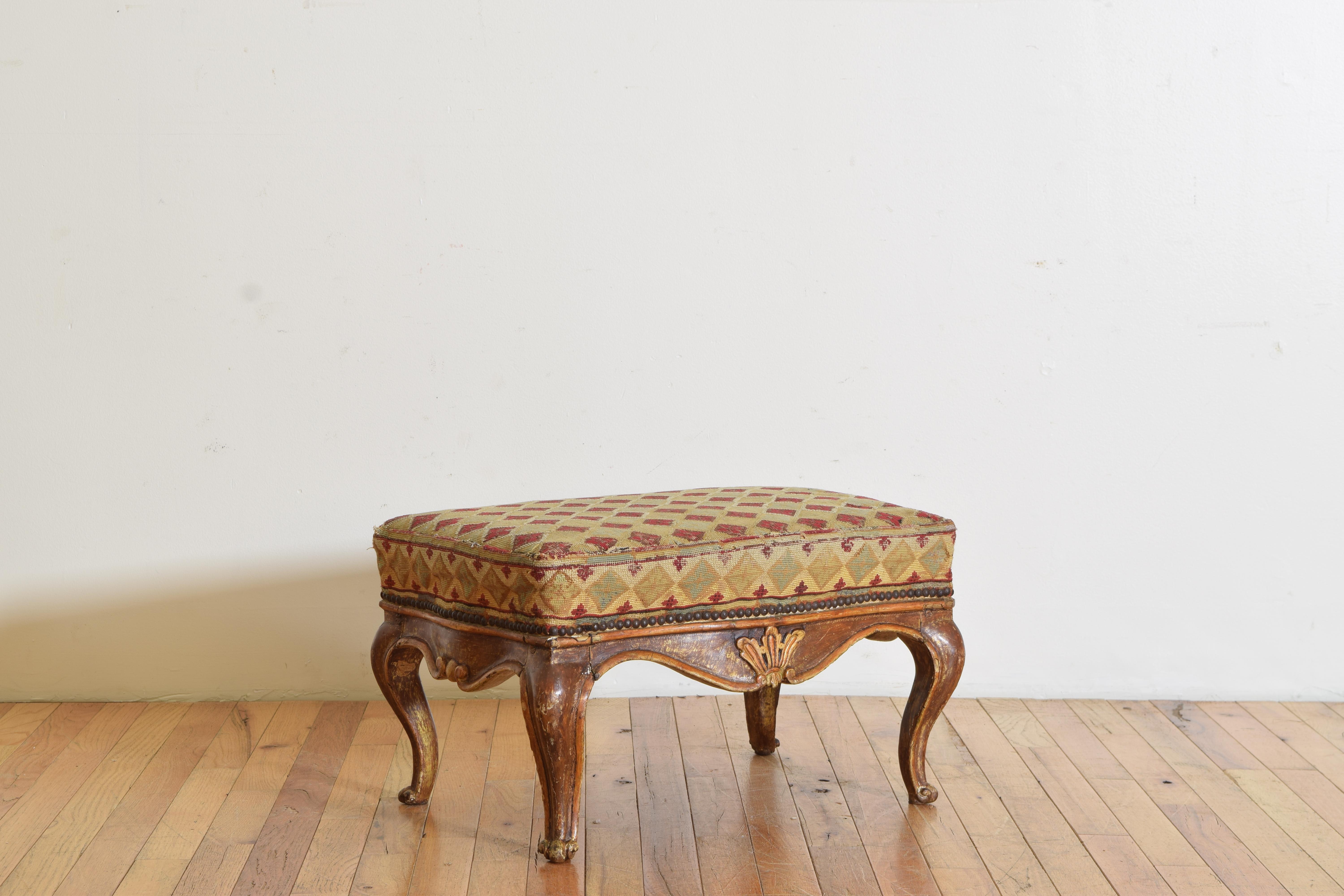 Having a jacard print needlepoint upholstered cushion trimmed in small nailheads atop a carved and shaped wooden frame that is lacquered and has giltwood details, the cabriole legs terminating in escargot feet.