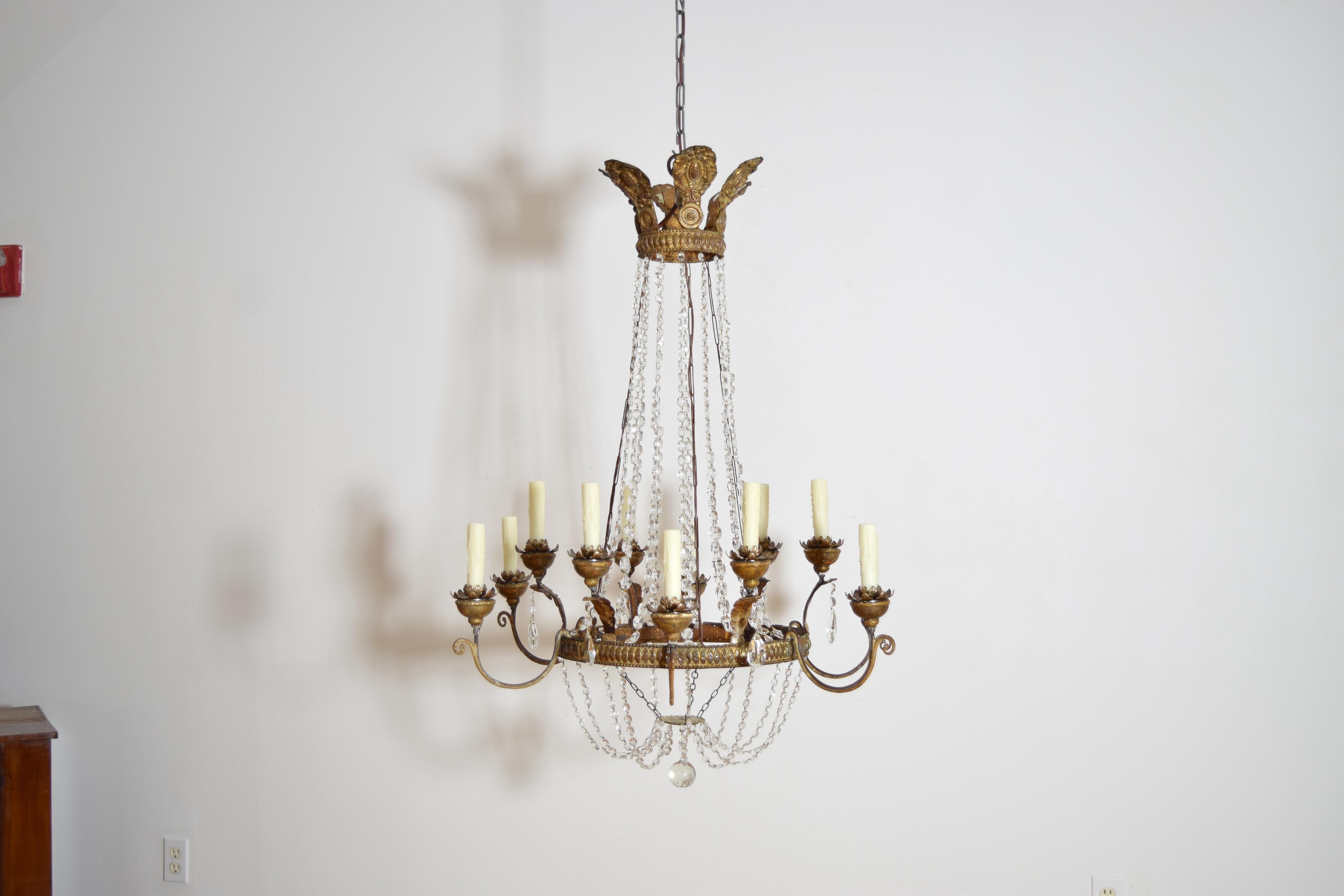 hanging from a gilt metal crown form top with roundels and leaf forms, the later glass bead chains connecting to a central ring sharing the same pattern as the upper crown and issuing two levels of a total of 12 arms, the arms with wooden bobeches