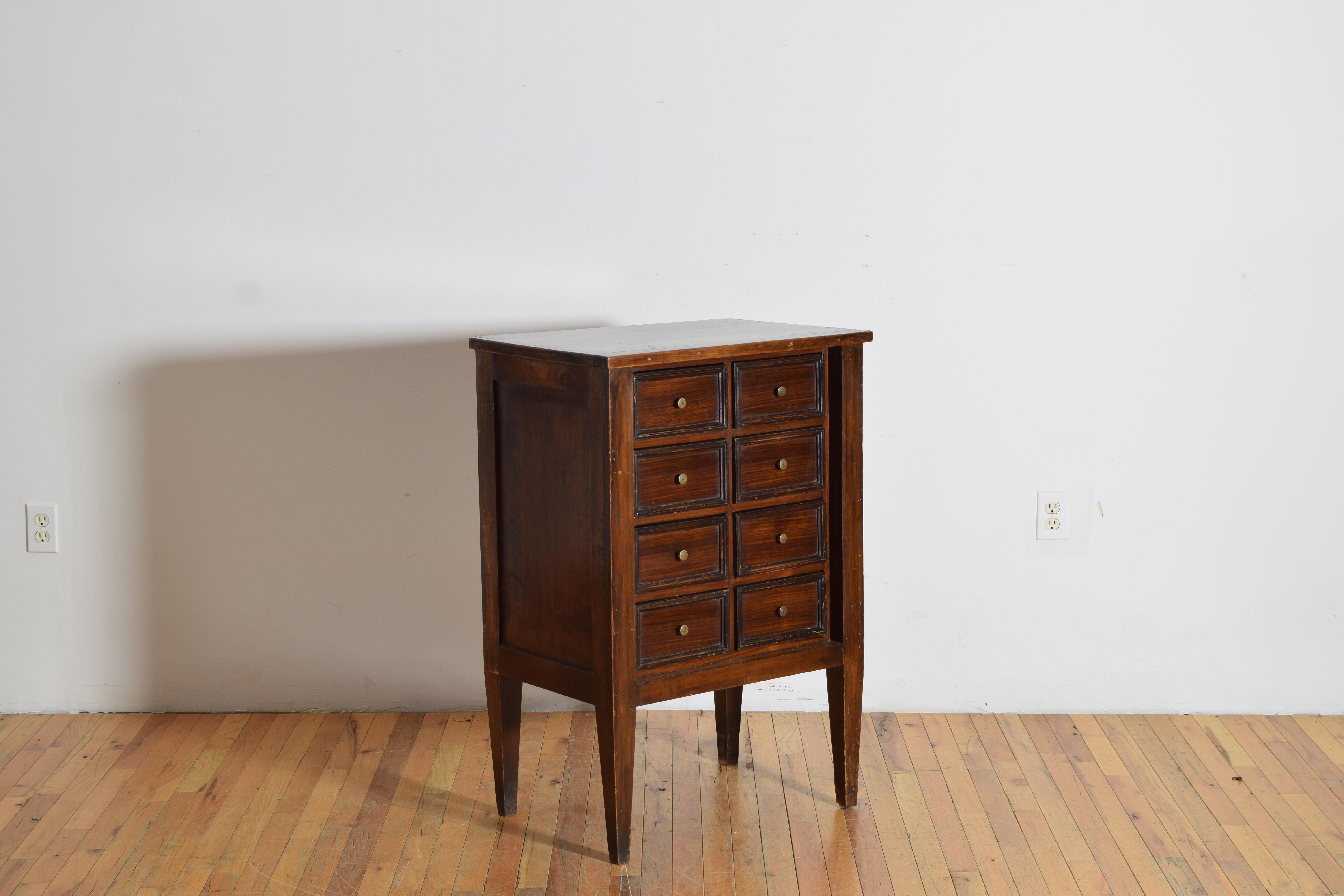 having rectangular top above a conforming case with slightly recessed sides and fronts, the front with 8 small drawers all trimmed in ebonized walnut, the case raised on square tapering legs