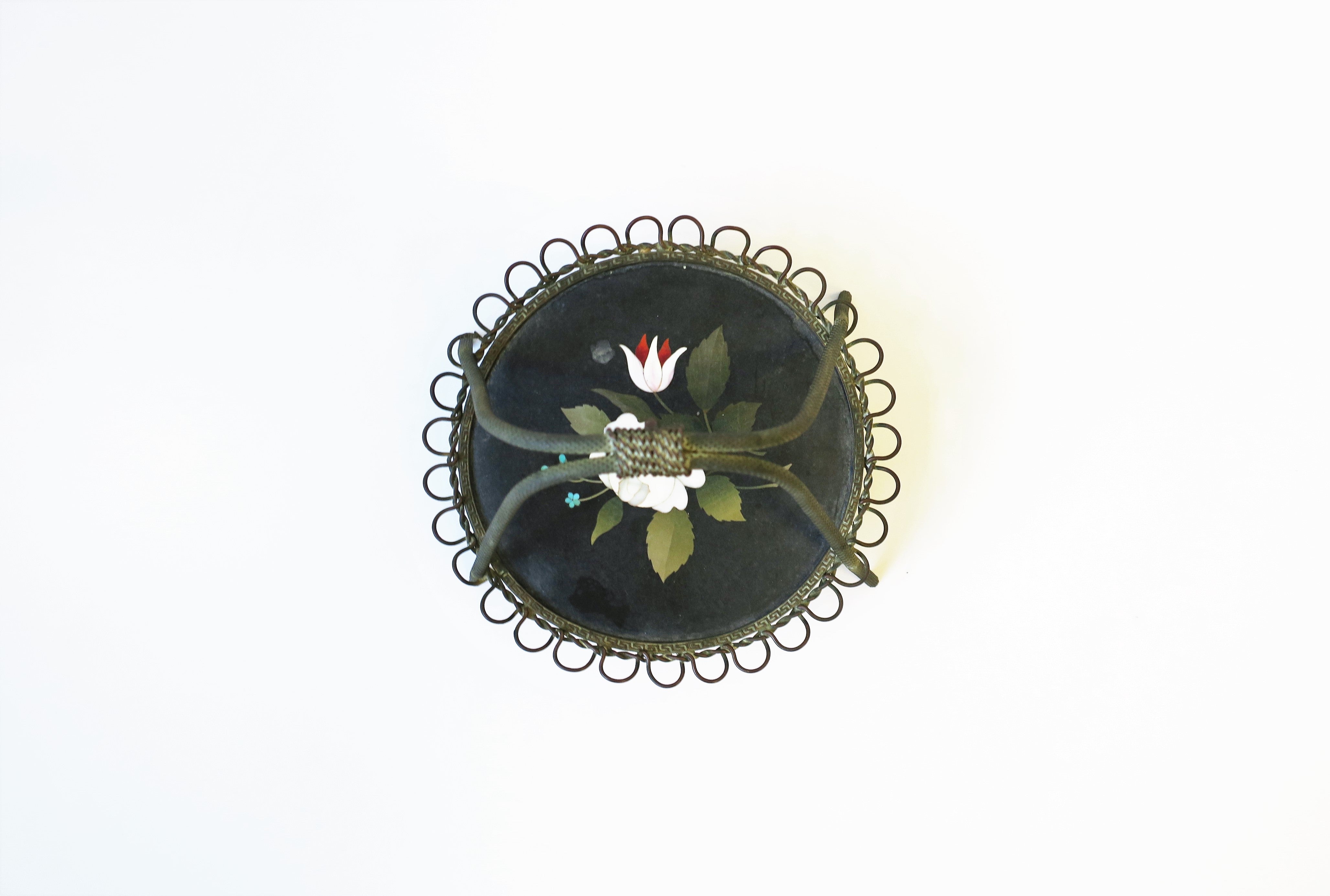 A very beautiful Italian Pietra Dura pocket watch stand with flower and leaf relief, circa early-20th century, Florence, Italy. Piece is a bronze or brass metal with a round black marble base with hand-cut inlayed marble and other stones. Pietra