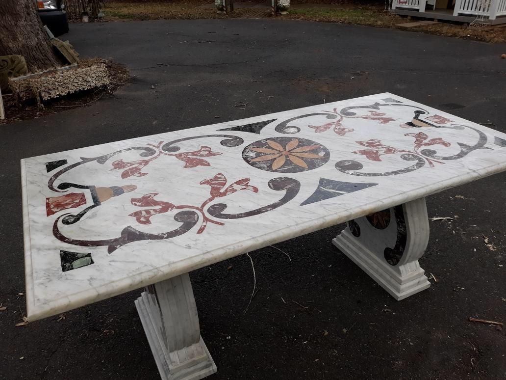 Stunning white marble with stone inlay Pietra Dura trestle table. The inlaid top with vibrantly colored inlaid store resting on two shapely bases with matched inlay. The inner corner of one base has a chip not seen when assembled.