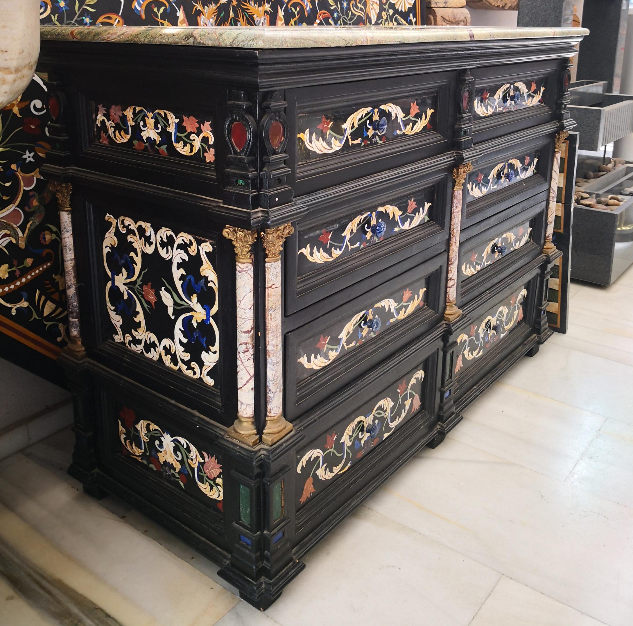 Palatial chest of drawers fully decorated by Italian craftsmanship using traditional pietre-dure hardstones inlay mosaics and brass accent pieces, mainly the pilasters base and capital. Forest-green marble tabletop. 

