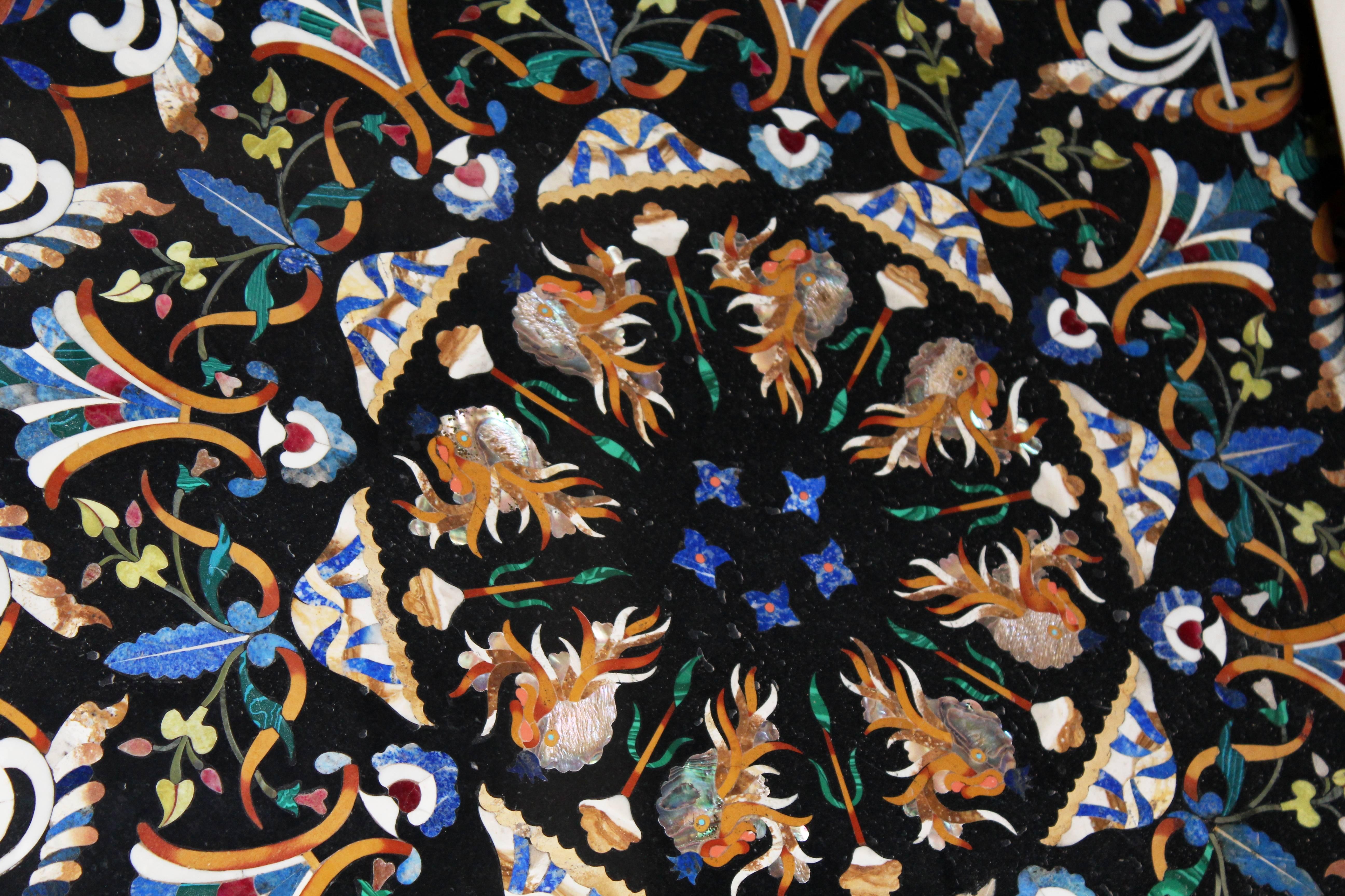 Handcrafted reproduction of an Italian 1700s ornamental design on black Belgian marble table top. Vases with flowers, clam shells, fishes and a myriad of elements are confirmed by the clever use of Pietre Dure, semiprecious hard-stones: green