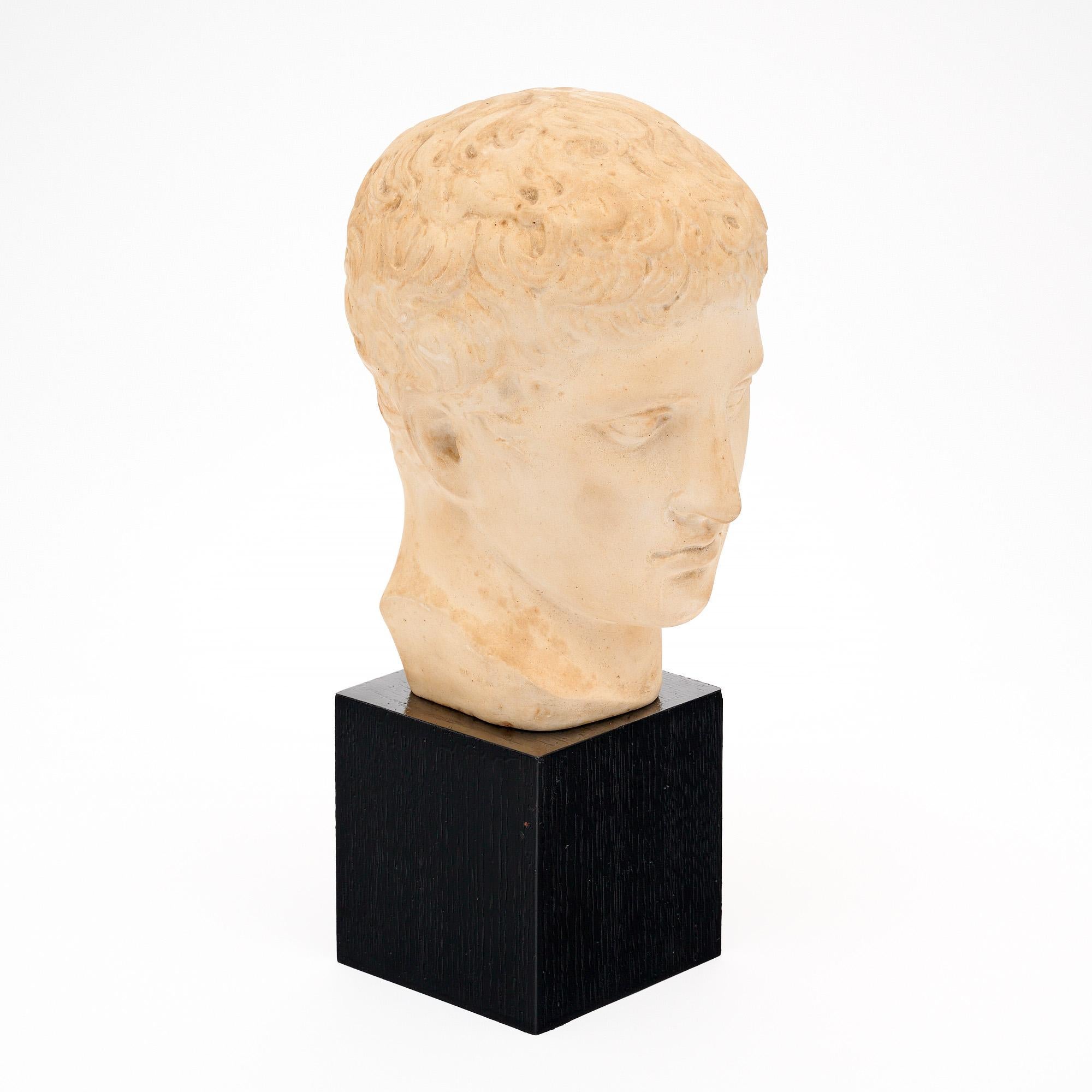 Buste ancien en plâtre d'Italie réalisé à la fin de la période victorienne, vers 1900. La sculpture est soutenue par une base en bois ébonisé. Le buste est un portrait de Doryphore, sculpté à l'origine en bronze par Polykleitos au Ve siècle avant