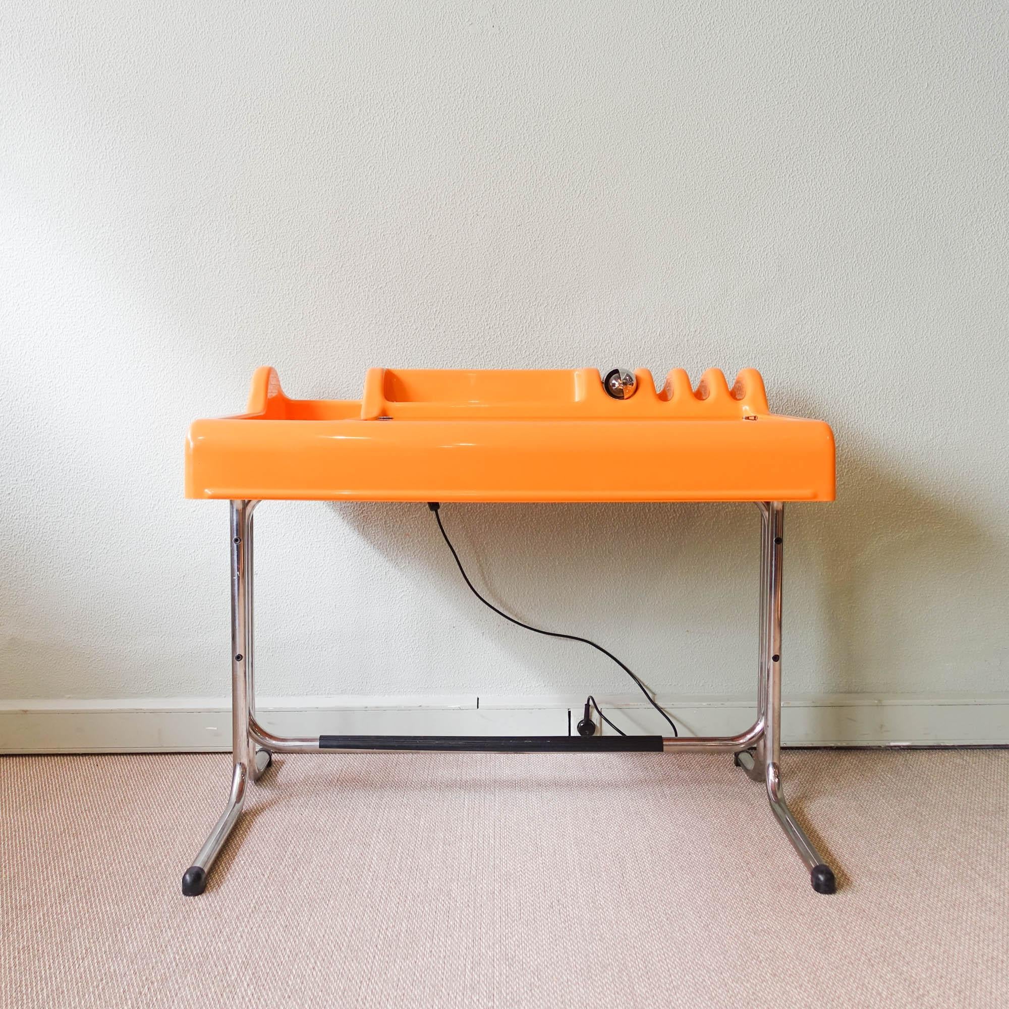 This orange desk, model 'Orix', was designed by Vittorio Parigi and Nani Prina for Molteni. It is in molded ABS plastic with chrome base, hinged glass writing surface and a built-in chromed lamp. It is in original and good condition, with some