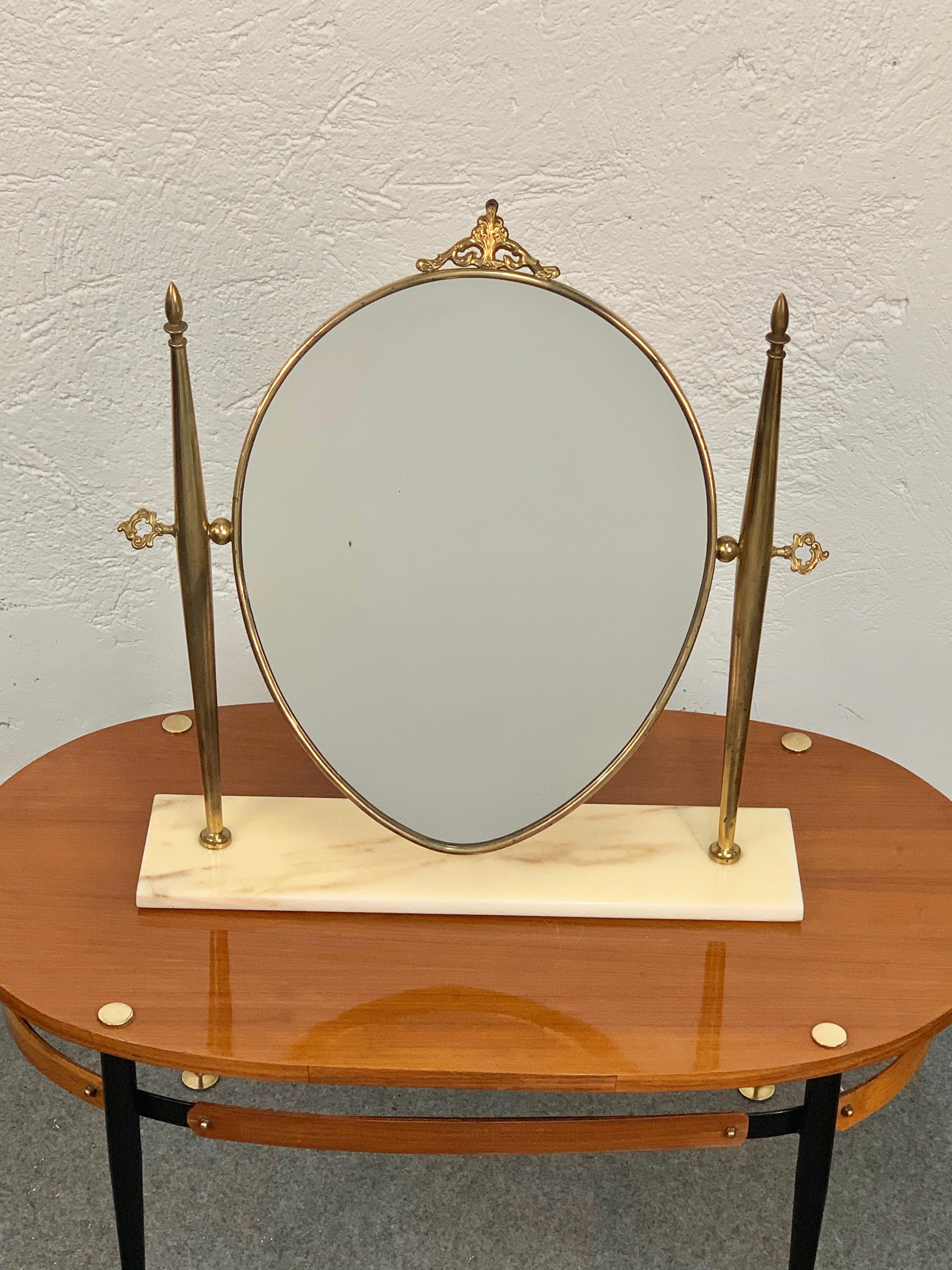 Wunderschöner Tischspiegel aus Messing mit verstellbarem Marmorsockel für den Waschtisch.

Dieser elegante Tisch oder Schminkspiegel aus der Mitte des Jahrhunderts wurde in den 1950er Jahren in Italien entworfen und hergestellt. 

Der Spiegel