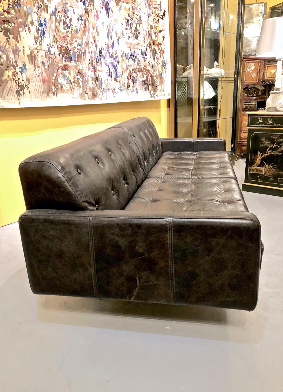 This is a chic example of a Poltrona Frau-style Italian leather sofa. The sofa is detailed in a multitude of buttons and features two loose seat cushions. The supple leather has acquired just the right amount of patina to add texture and interest.