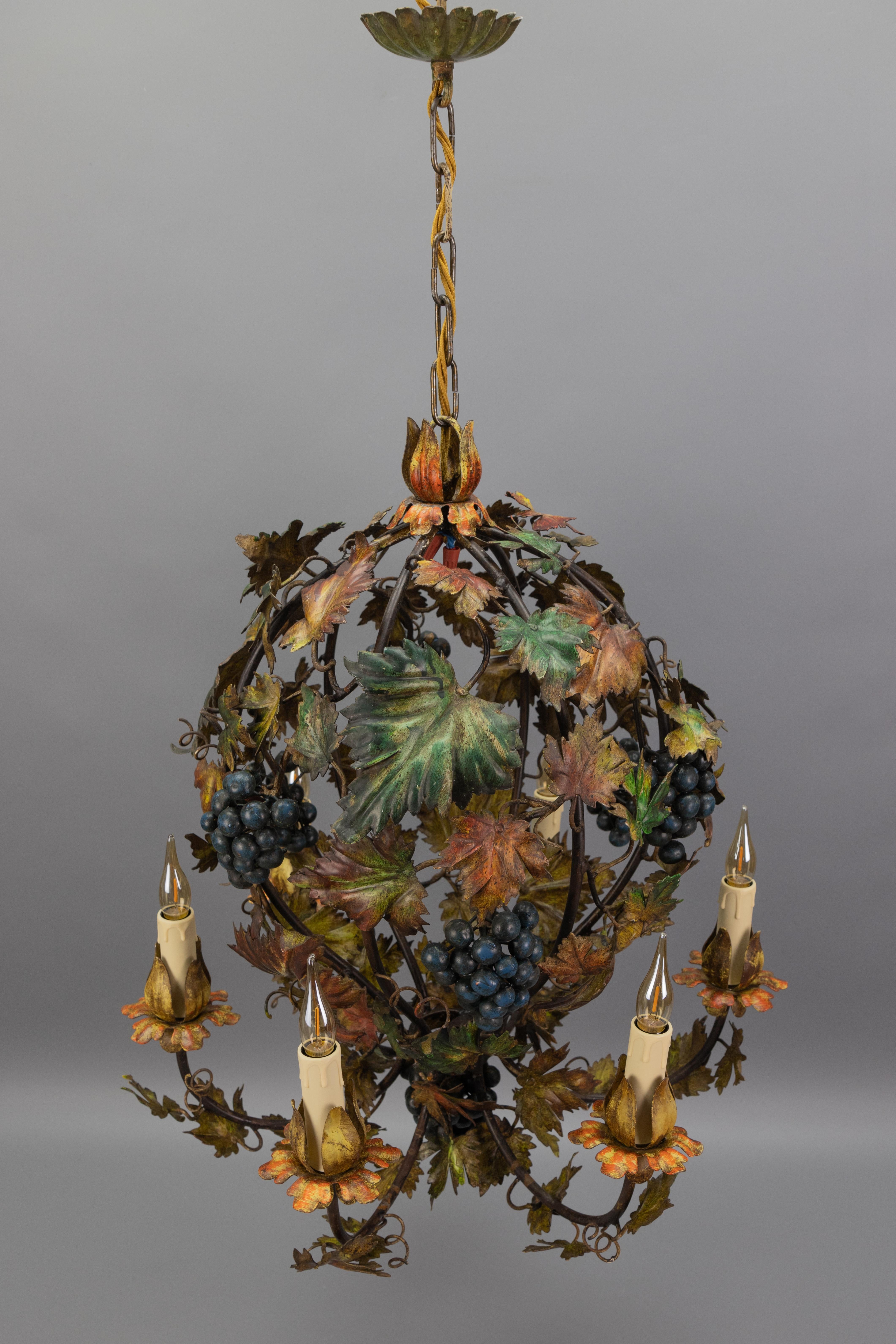 Lampadario italiano a sei luci in metallo policromo con uva, viti e foglie colorate d'autunno, anni '50 circa.
Questo eccezionale e bellissimo lampadario a forma di mongolfiera è realizzato in metallo nei toni del verde, blu, marrone e giallo scuro.