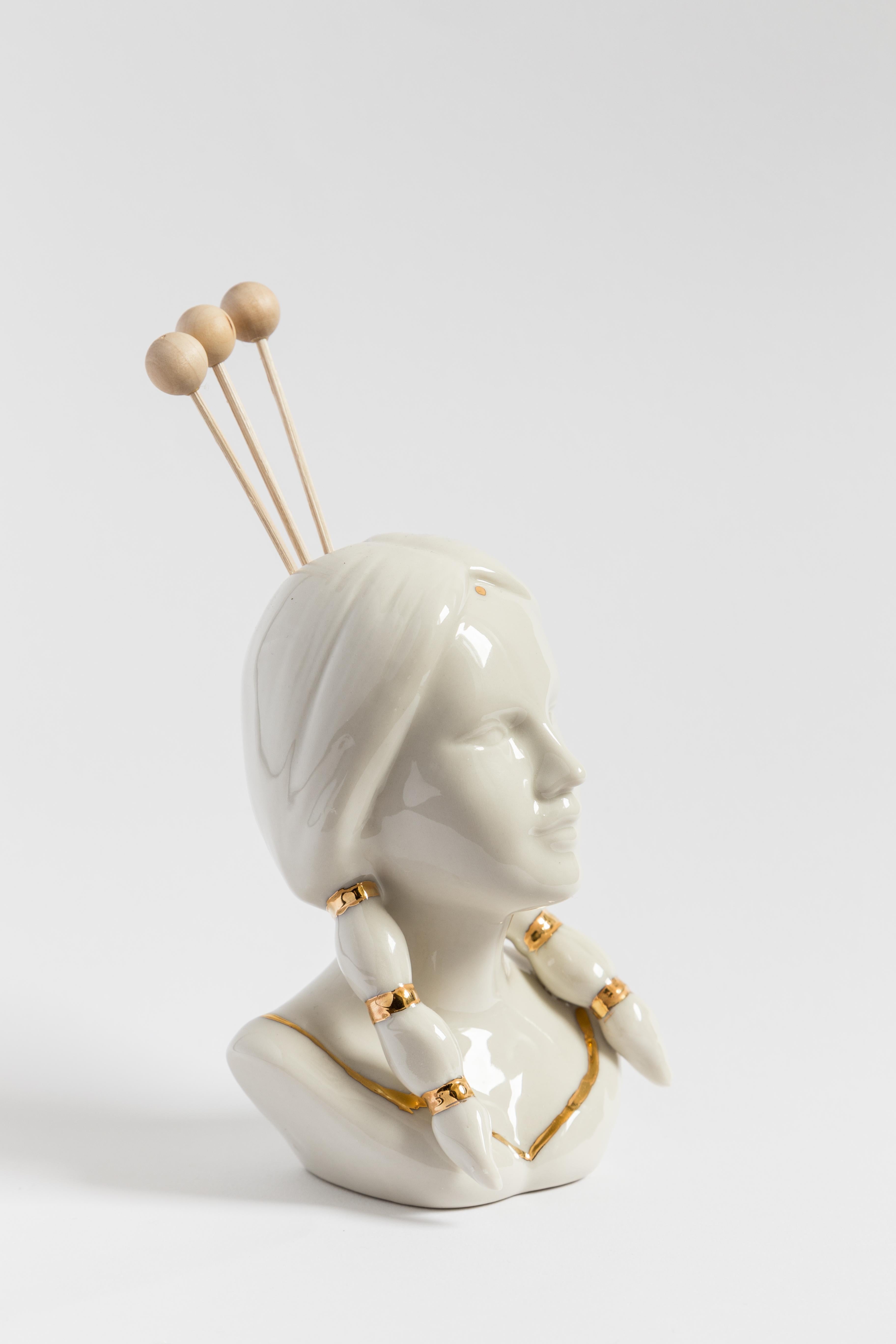 This Italian porcelain sculpture is part of Grand Tour by Vito Nesta. Made in Capodimonte porcelain with a glossy finish and gold detail, this sculpture is an essential oil diffuser and is shaped like a Native American woman.