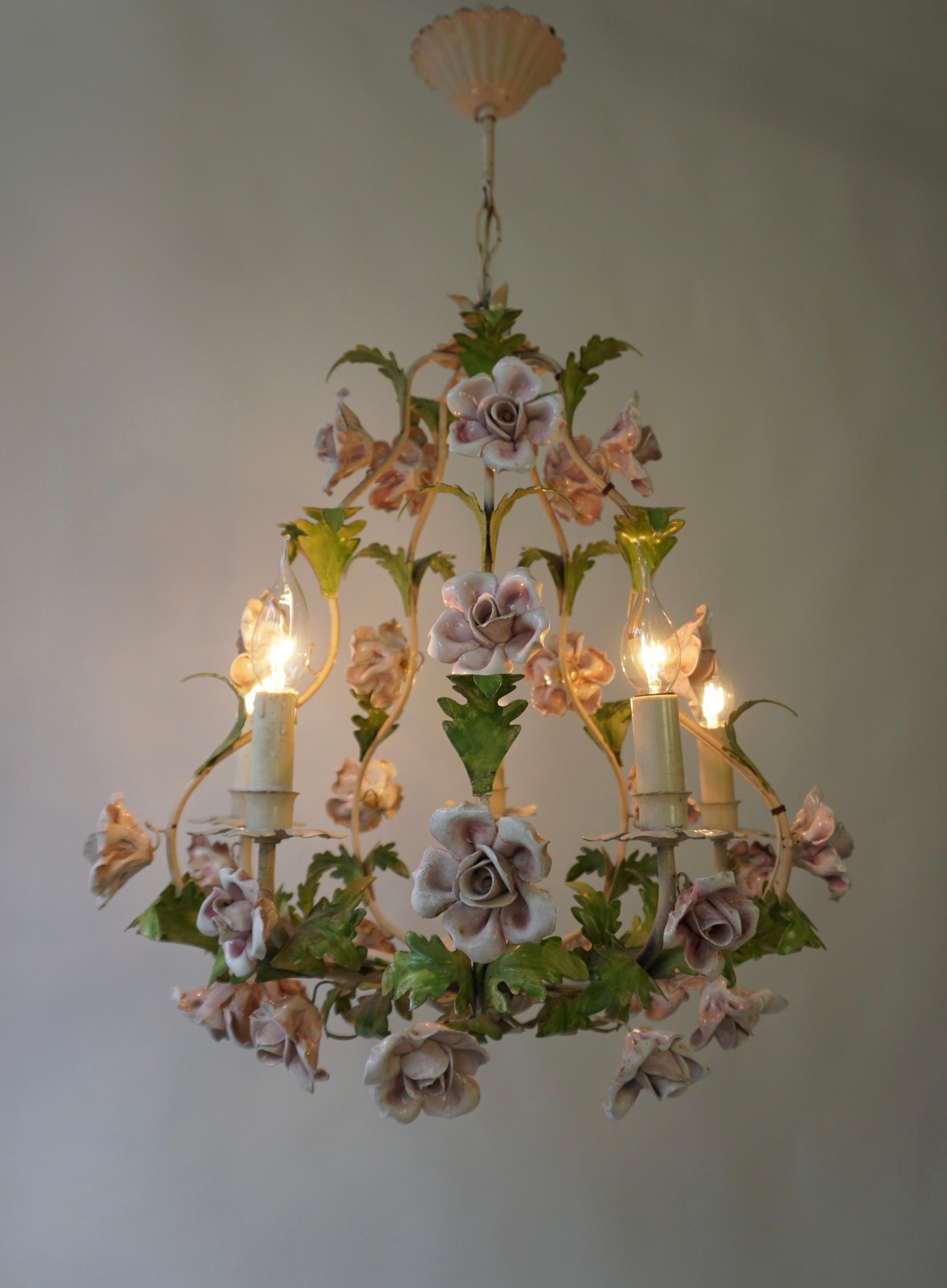 An Italian handcut tole chandelier. The cage form metal frame ornamented with tole leaves, and pink-white porcelain flowers. 

The chandelier has five sockets for small incandescent lamps with screw base or E14 type LEDs. It is possible to install