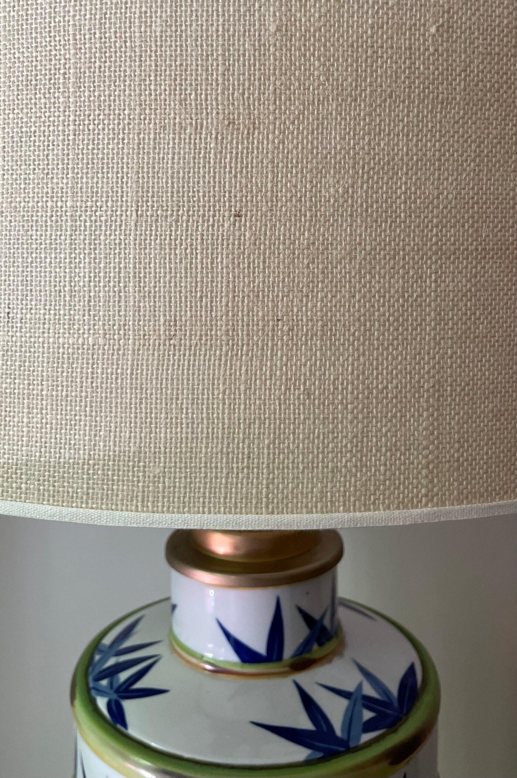 Table lamp with porcelain base decorated with bamboo leaf motifs. Original burlap lampshade. Italy, 1950s.

Height: 79cm
Lampshade diameter: 50cm
Body diameter: 24cm
