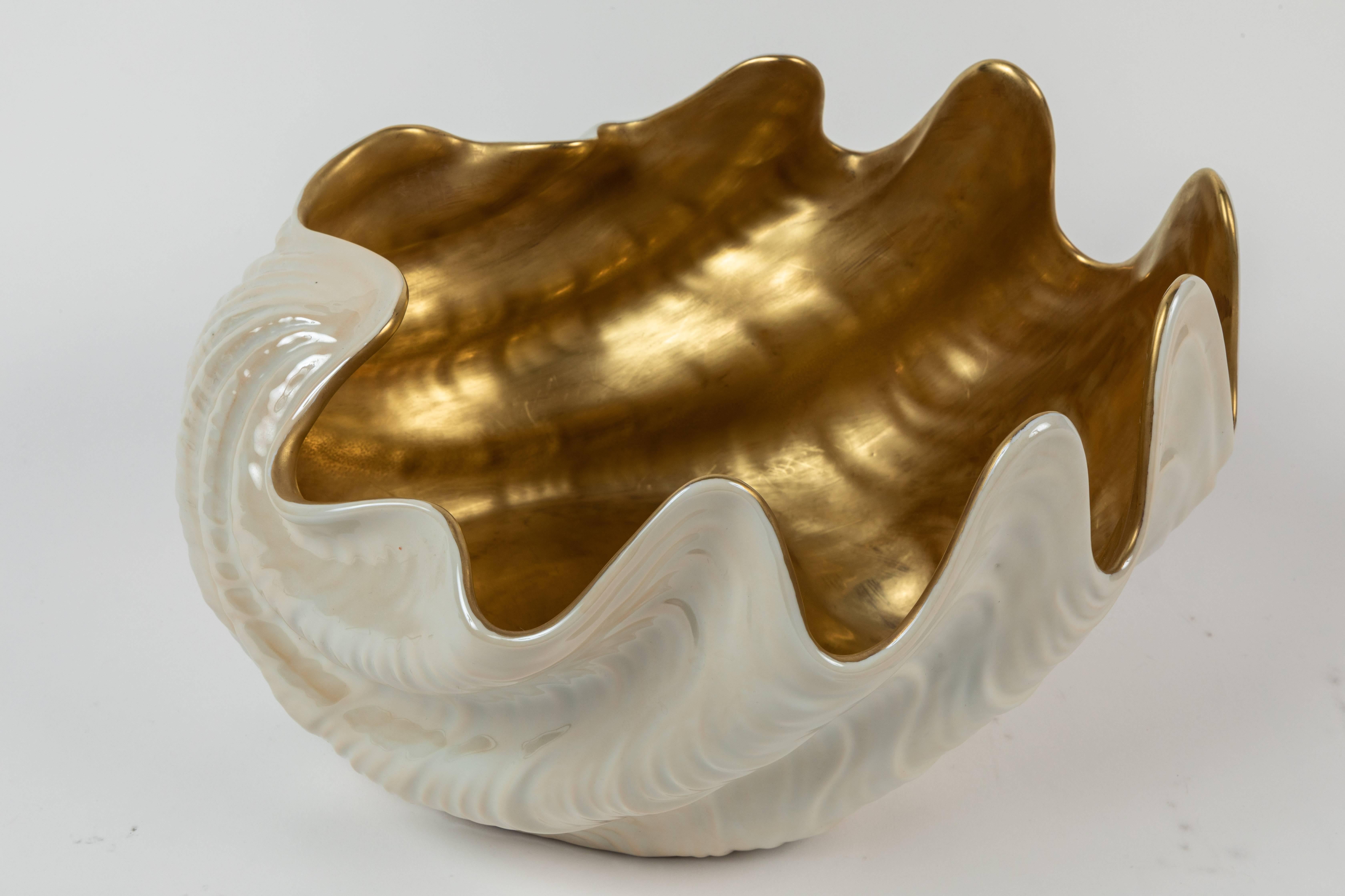 Large and stylized porcelain shell Dorn bowl. The exterior of the shell has a glazed porcelain finish while the interior is a luxurious gold finish. Impressive scale.