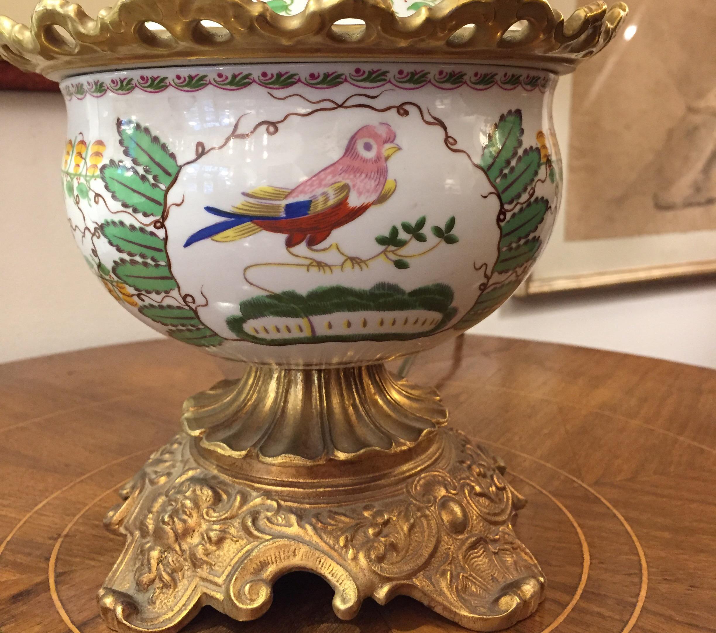 Lampe de table Mangani Firenze en porcelaine et bronze doré, vers 1970, une lampe à huile circulaire en porcelaine montée sur un socle en bronze doré, un vase en porcelaine avec un décor polychrome tout autour représentant des oiseaux et un