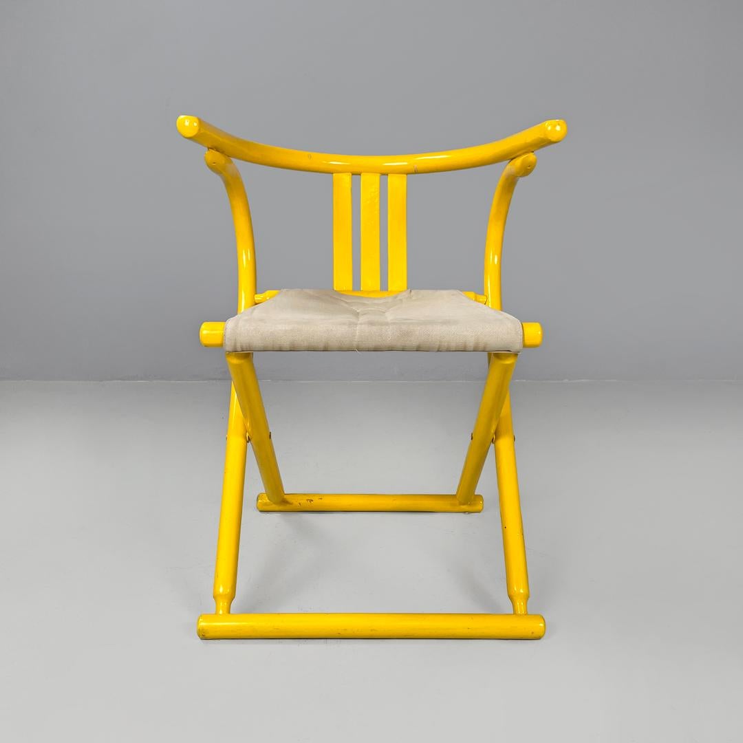 Italian post-modern folding tub chair in yellow wood and beige fabric, 1980s
Folding cockpit chair with yellow painted wooden frame. The frame has a round section, and comprises the enveloping backrest and crossed 