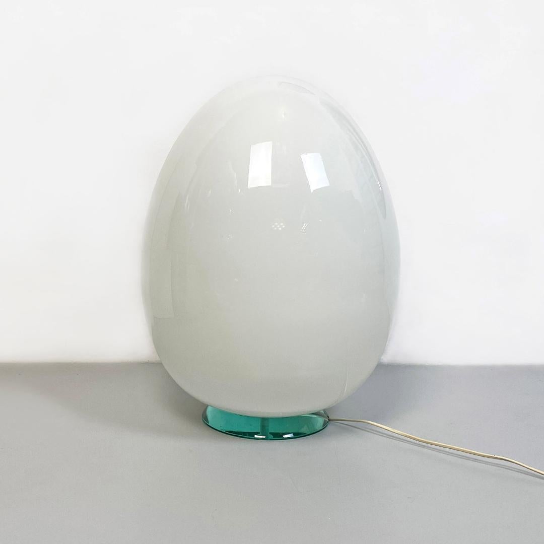 Italian post modern milk glass table or floor egg lamp with acquamarine base, 1980s.
Table or floor lamp with egg-shaped diffuser in milk white glass, with housing on a round base in aquamarine green crystal.
1980s
Good condition, small mark on