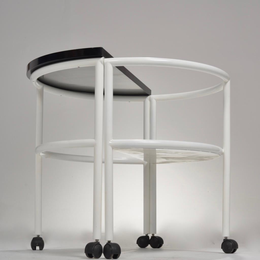 This round Postmodern writing desk is on casters for easy mobility and transportation. The half-moon seat of the desk is attached to the half-moon table top to create a complete circle when closed. The seat is attached by hinges and can be swung