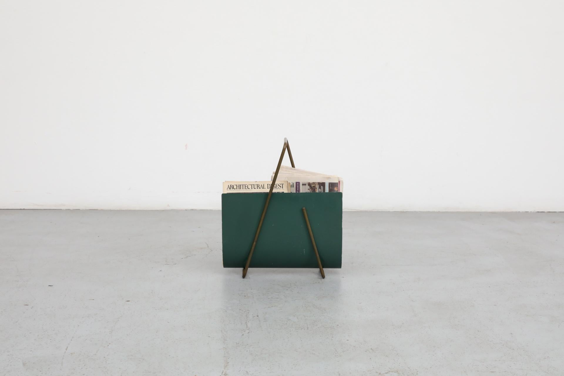 Interessante portariviste italiano Post Modern dal geniale design minimale ma dallo stile notevole. È costituito da un unico pezzo di tubolare d'acciaio piegato e da un foglio di lamiera smaltata e sagomata color verde acqua. Graffi e usura tipici