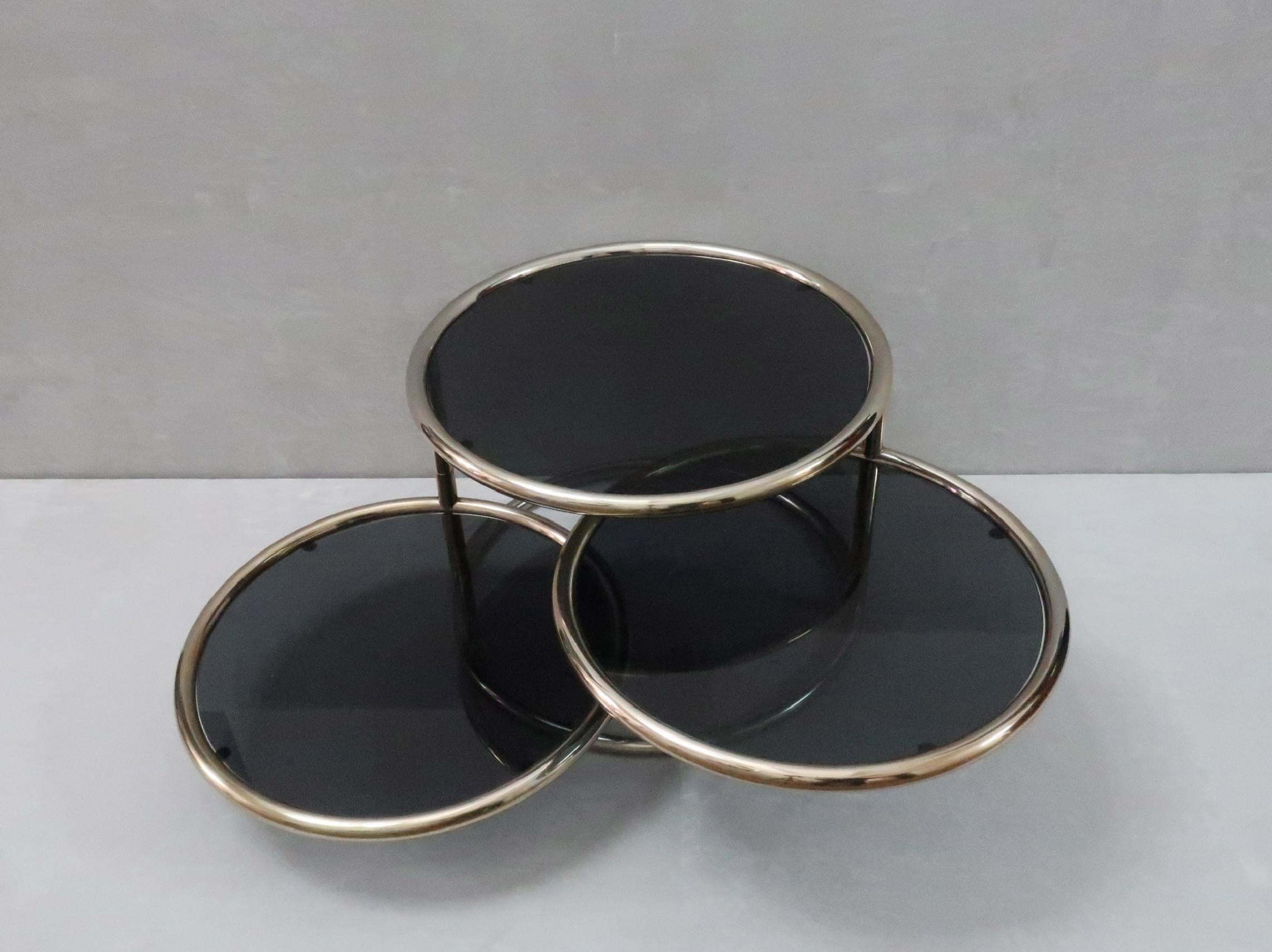 Une table basse ou table d'appoint italienne des années 1970 à trois niveaux et à deux niveaux pivotants constitue un meuble très fonctionnel qui peut être allongé ou compact. Le cadre de la table est en acier tubulaire doré et le verre fumé repose