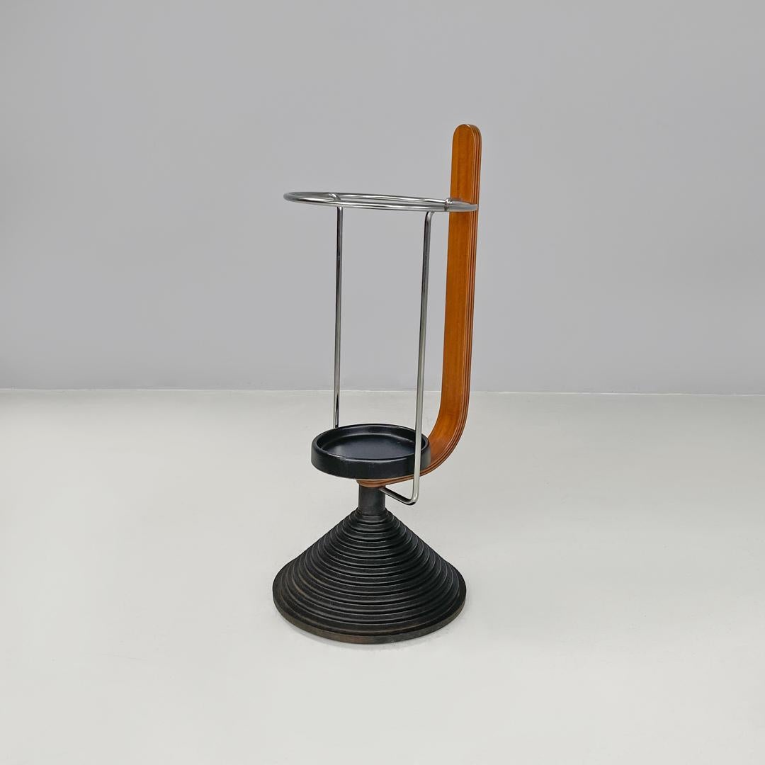 Italian postmodern round umbrella stand by Origlia in wood and cast iron, 1980s
Round umbrella stand, with round chromed metal rod structure and a rounded wooden strip. The plate at the base of the structure is made of black synthetic material. The