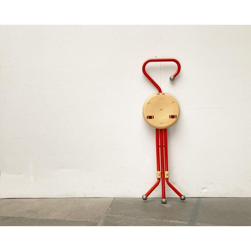 Postmodern folding stool from the Italian manufacturer Sandrigard after a design by Ivan Loss from the 80s.

An elegant and extremely functional design. The stool can be used as a walking stick when folded. The upper end of the frame is bent into a