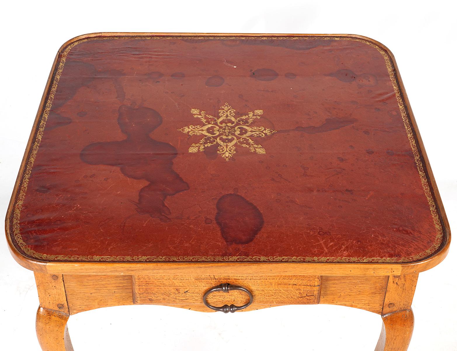 This Italian late 18th century table features a leather gilt tooled tray style top centering an elaborate star motif above a shaped frieze with one drawer raised on slender cabriole legs ending in stylized hoof feet.