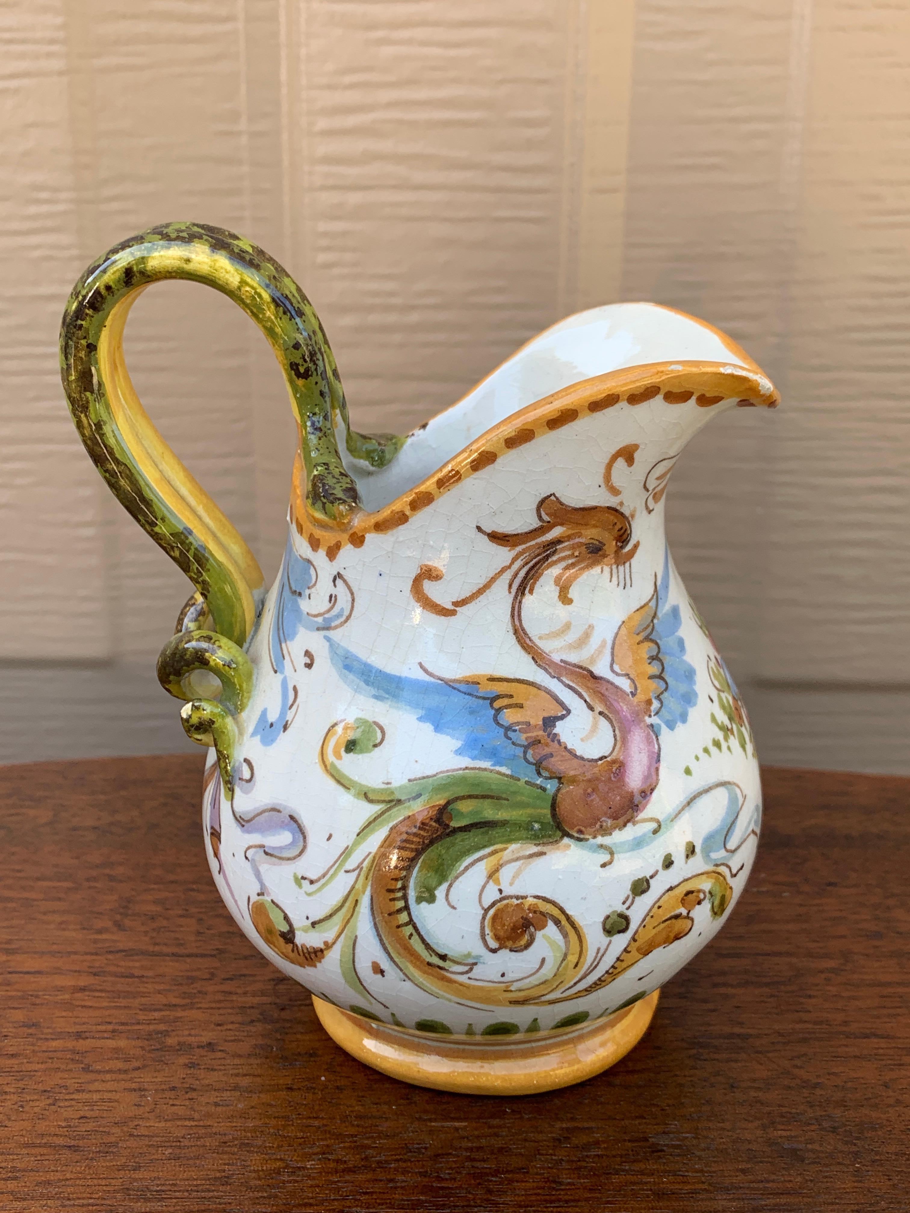 A beautiful hand painted blue, white, yellow, and green faience pottery jug or vase featuring dragons and floral designs.

By Deruta

Italy, Late 20th Century

Measures: 4.25