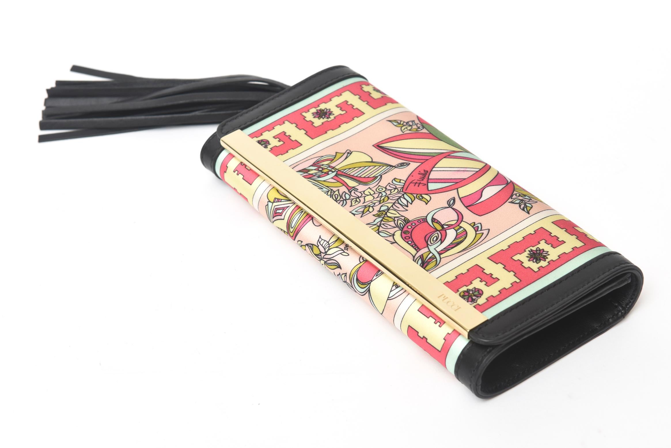 This happy and beautiful Italian Emilio Pucci silk and black leather tassel small clutch / wallet is gorgeous. It has black leather trim with a gold tone bar and a long tassle on one side. This is perfect for resort and cruise wear of 2023. For