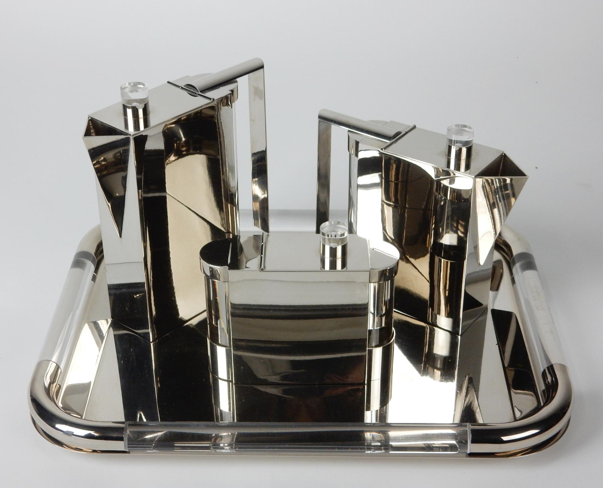 High quality tea service set designed by Punto Bacola for Montagnani of Florence, Italy, circa 1980. 
Formed of sculptural polished nickel with Lucite side/end caps and finials. 
Marked with gold label 