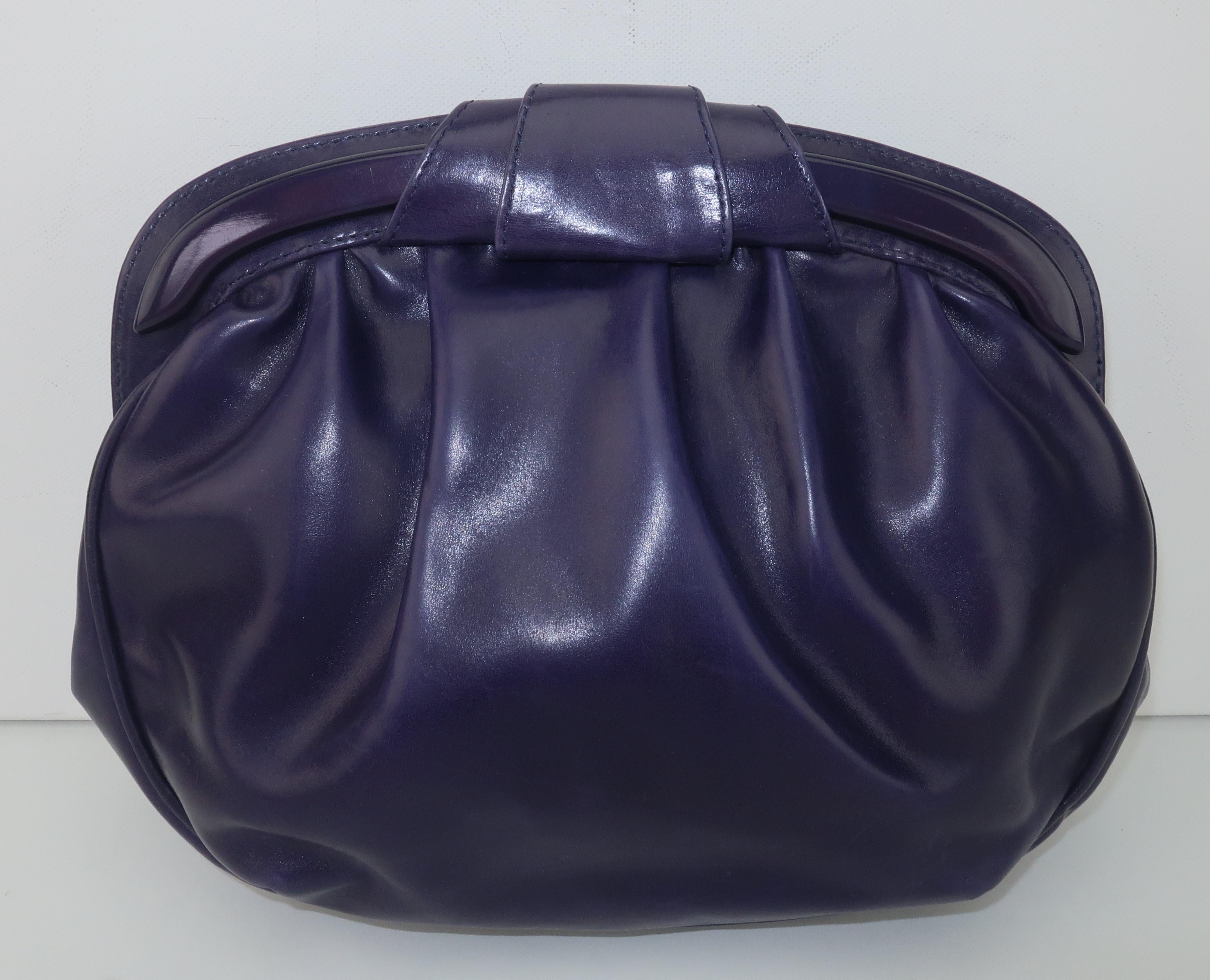 An Italian leather handbag by Chanteuse in a wonderful shade of purple best described as grape.  It has a snap closure at the top of the frame with a coordinating decorative resin bar and top knot for added visual interest.  The lengthy shoulder