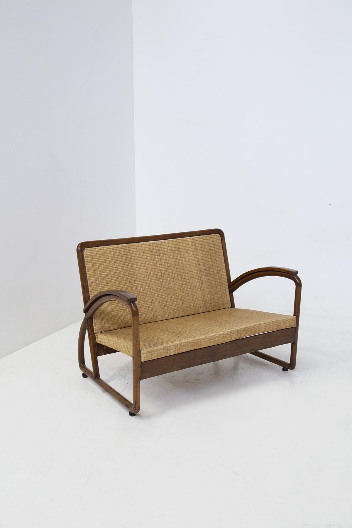 Beautiful loveseat from the Italian rationalist period of the 1920s.
The loveseat was made from fine wood for the frame and rattan for the seat and back. 
Its bold, sharp and enveloping forms are precisely to be attributed to the historical period