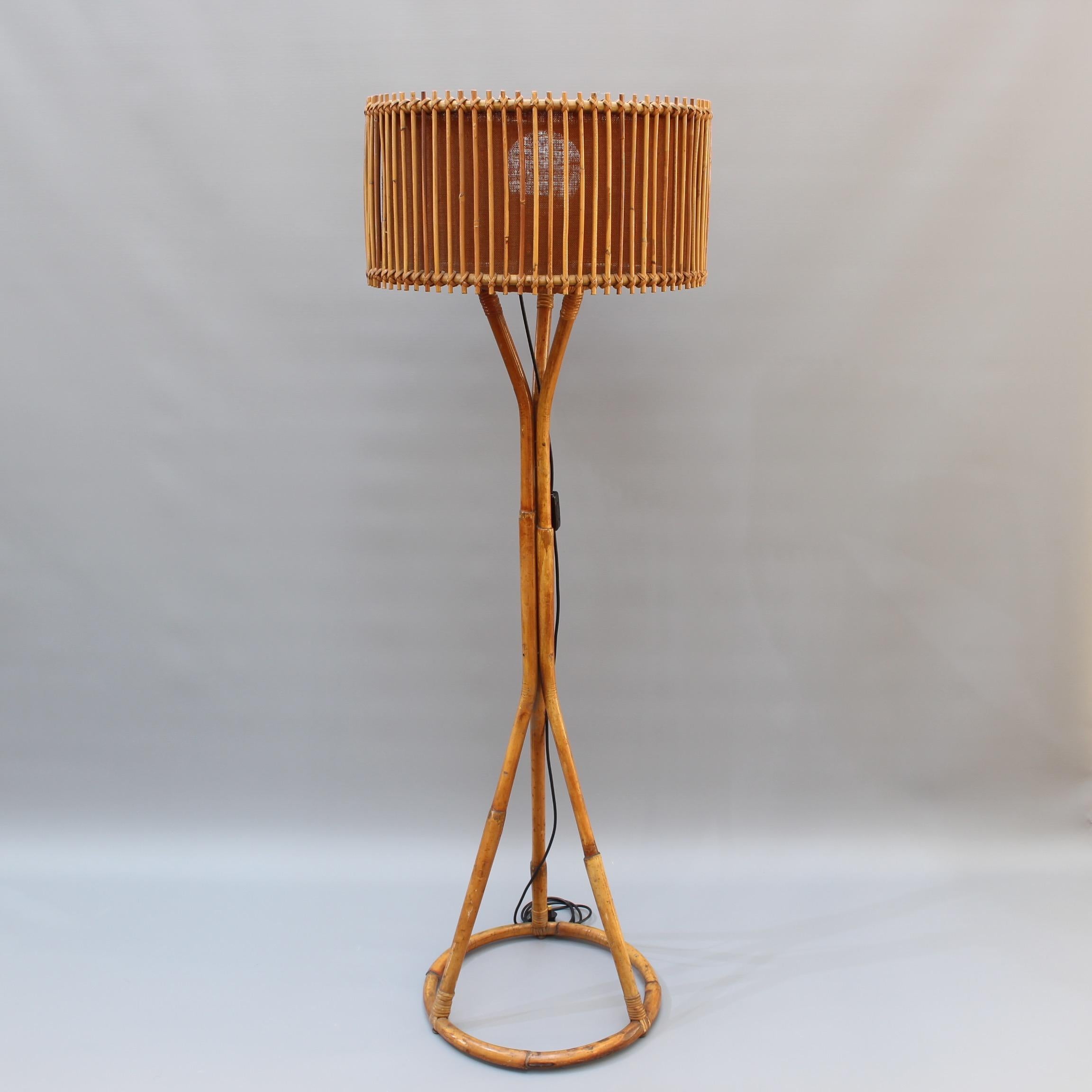 Italian rattan and bamboo floor lamp, circa 1960s. A circular bamboo base provides the stylishly supporting attachment points for three legs which intertwine to form the main structure of this elegantly simple design. The shade is formed by rattan